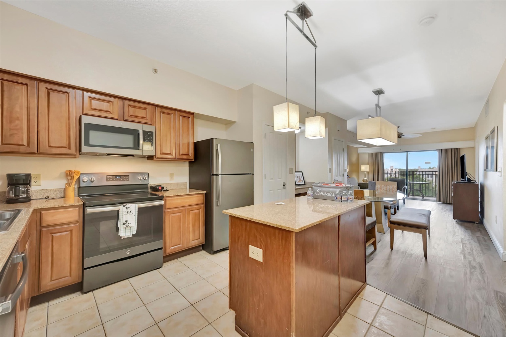 Well-appointed kitchen with stainless steel appliances and island counter space. Open-concept living and dining areas with natural light from the balcony—perfect for relaxing or entertaining.