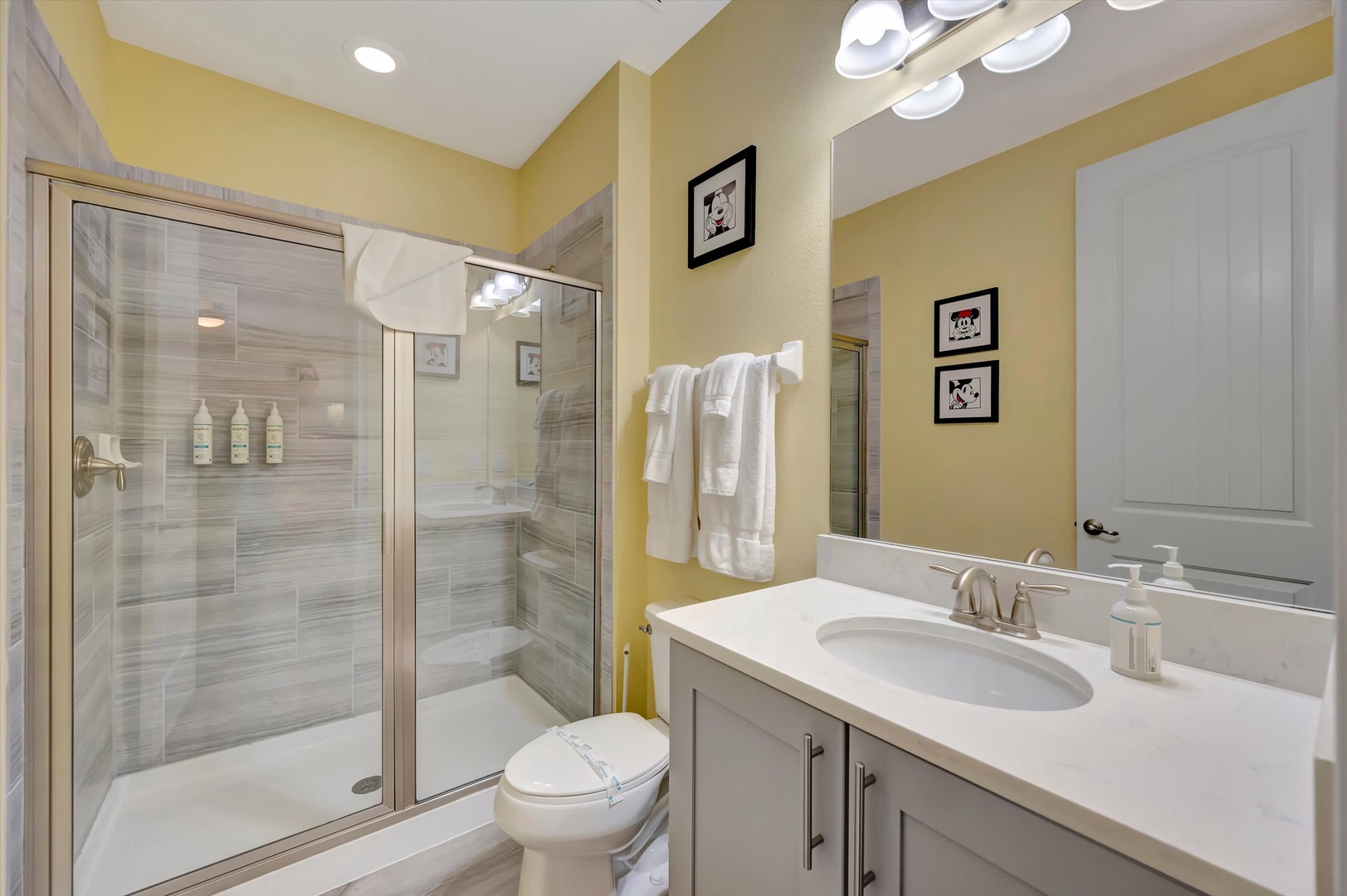 Step into this cheerful bathroom with warm yellow walls, a spacious glass-enclosed shower, and fresh white towels waiting for you. Everything you need to refresh and unwind after your adventures.