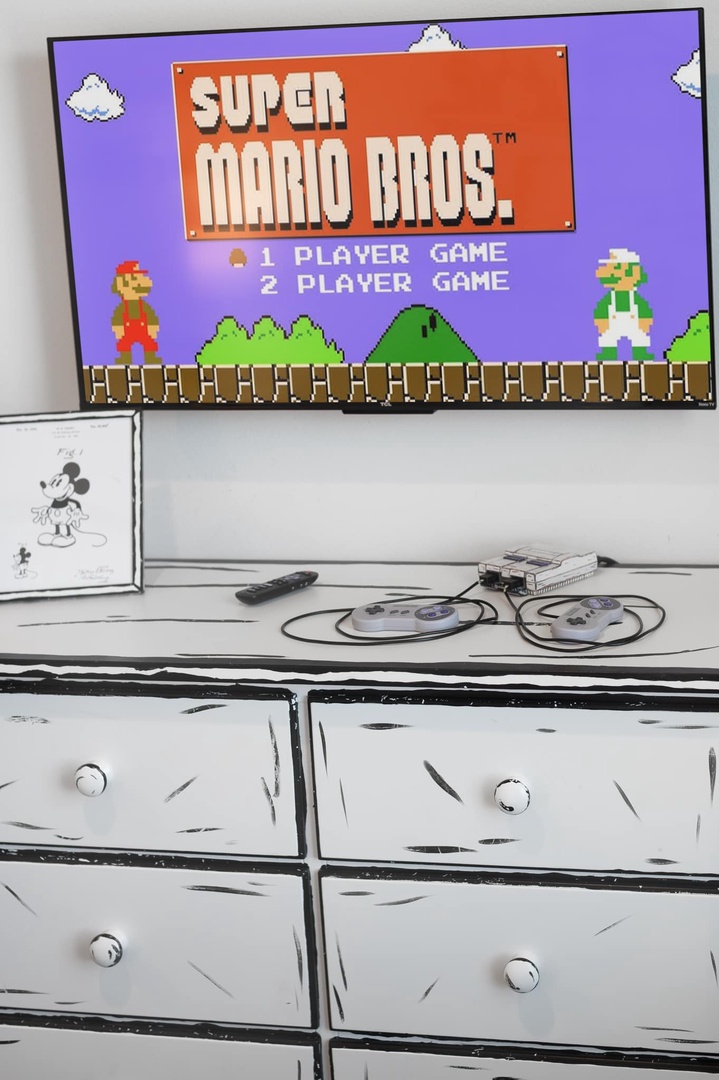 Vintage gaming console with controllers sits ready for your entertainment, mounted above a rustic white dresser—perfect for downtime between adventures.