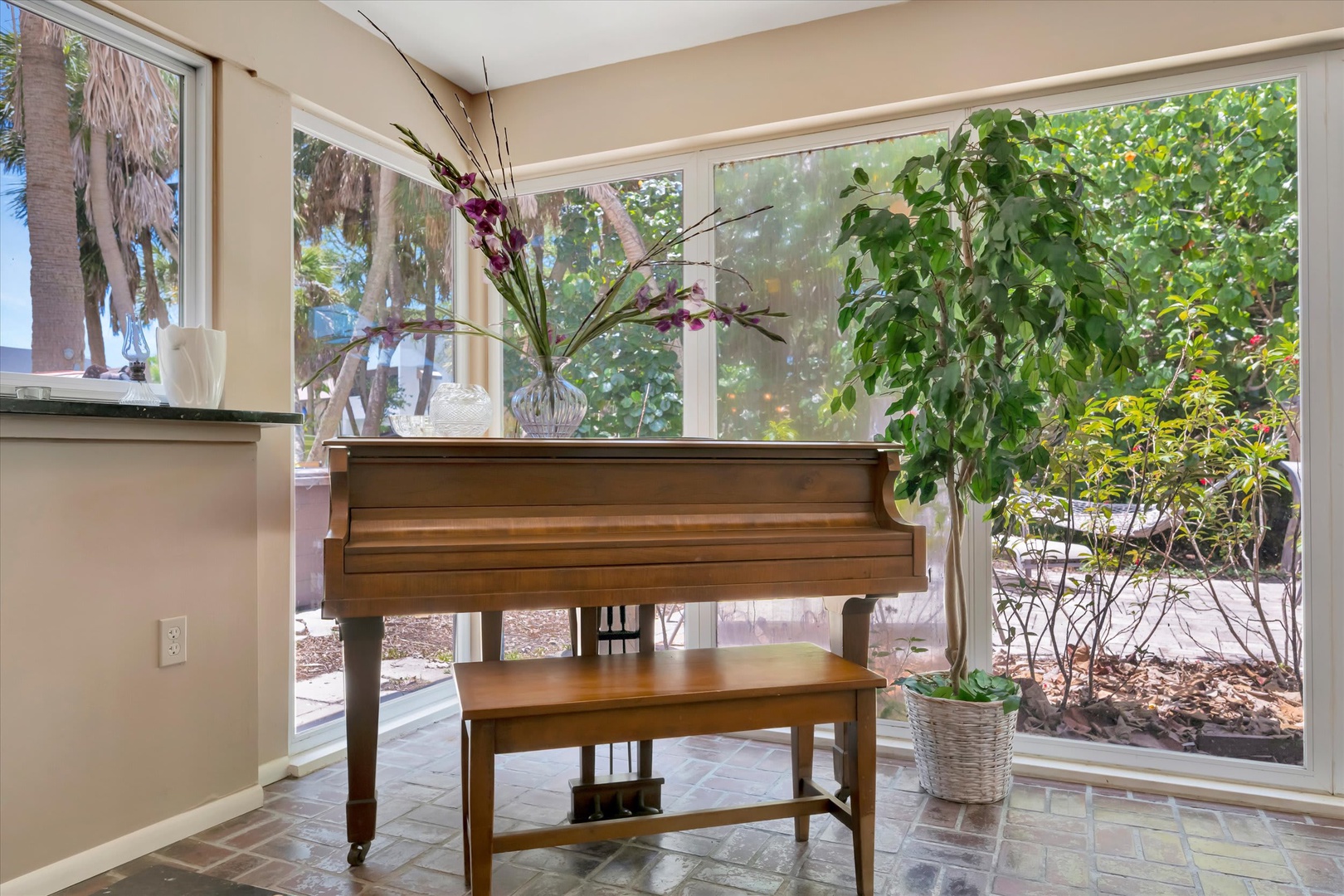 A warm sunlit space where your creative spirit can flourish, framed by lush greenery just beyond the windows.