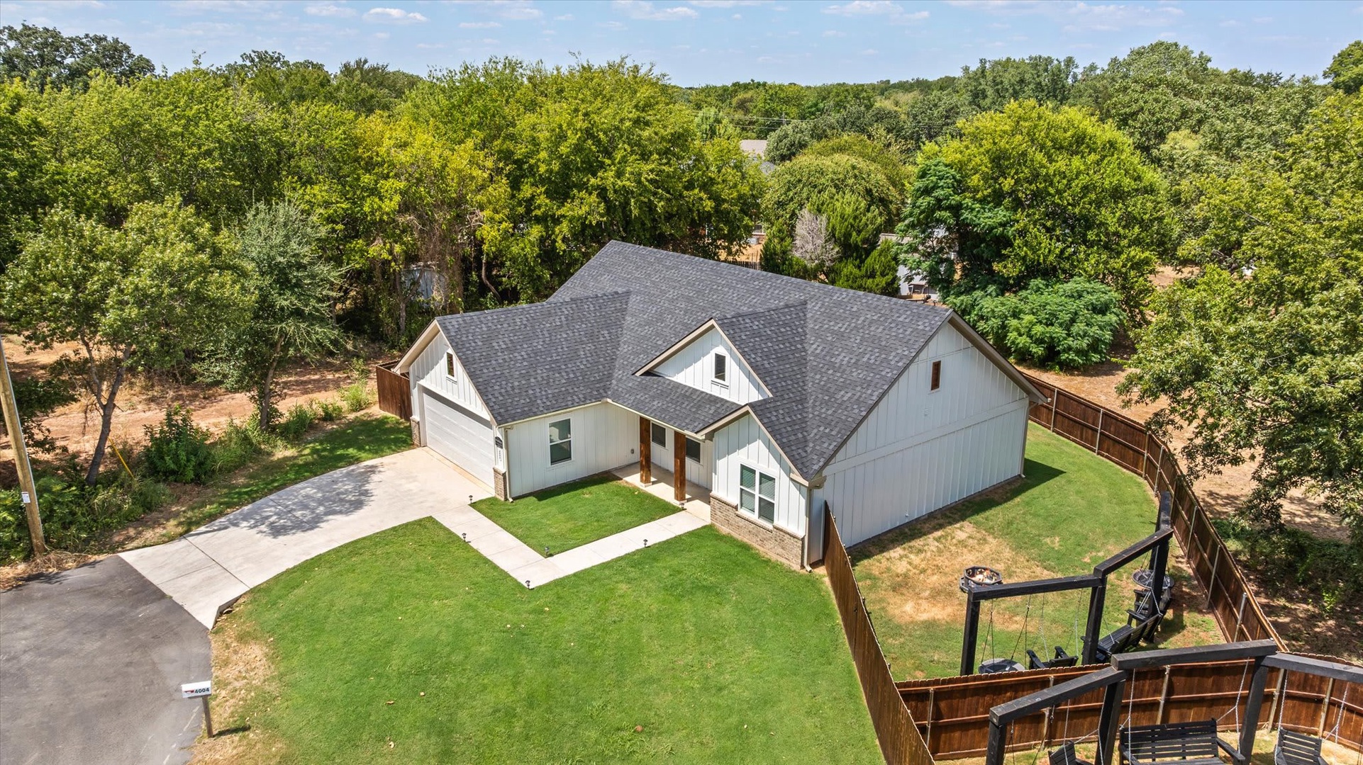 An aerial view captures the property surrounded by mature trees and greenery in a peaceful neighborhood setting.