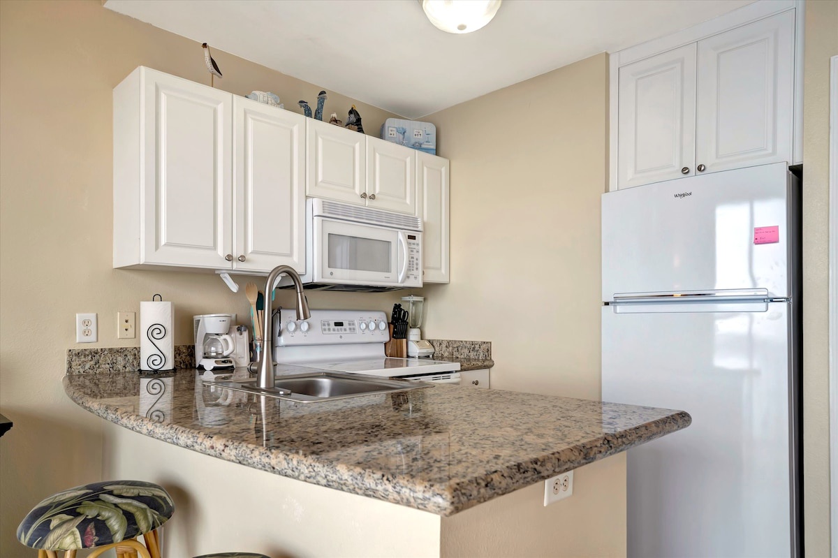 Your fully equipped kitchen awaits with crisp white cabinetry, gleaming granite countertops, and modern appliances ready for your morning coffee or a home-cooked meal.