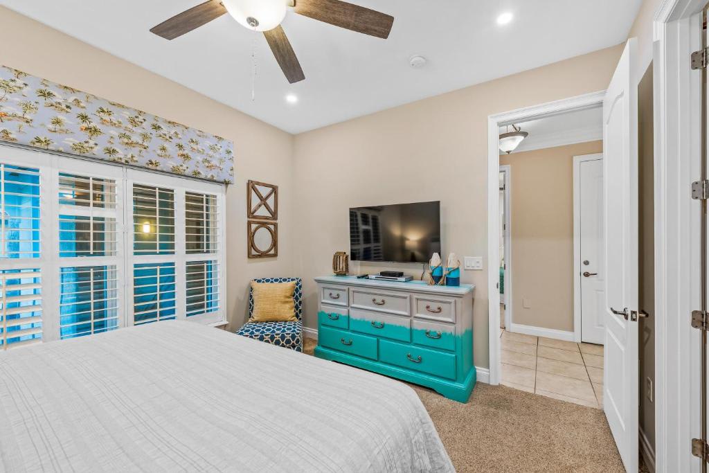 Unwind in your bright, breezy bedroom featuring coastal-inspired décor, a ceiling fan for comfort, and a cheerful pop of turquoise to set the perfect vacation mood.