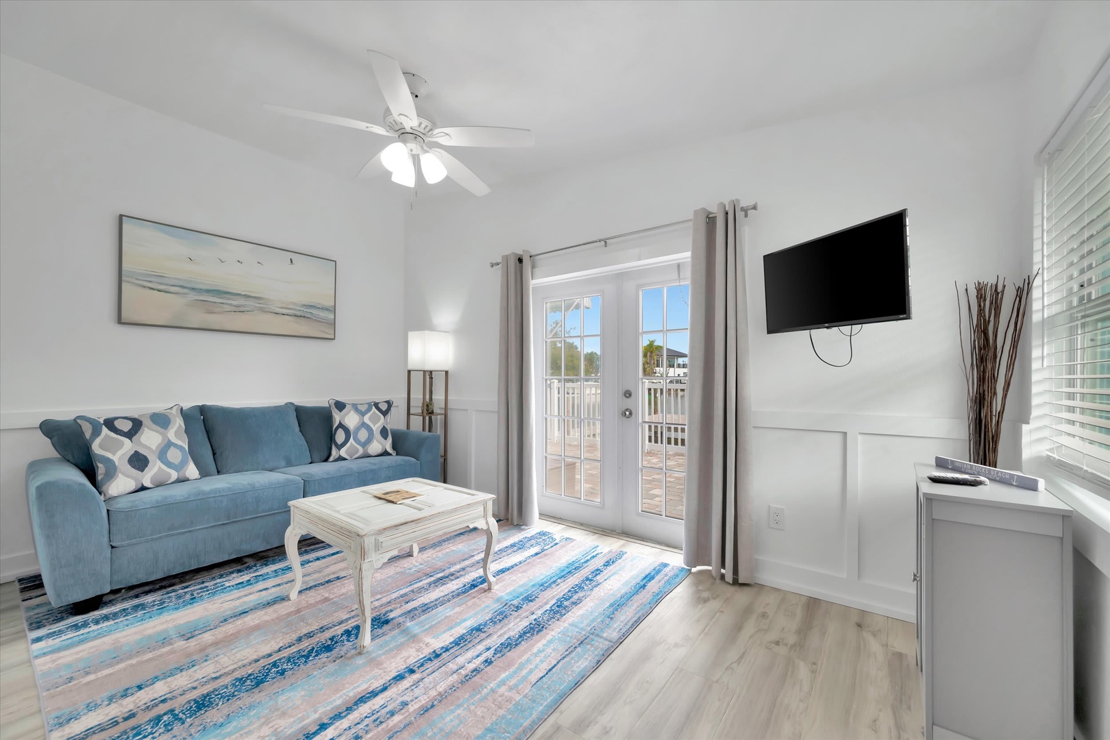 Relax in your bright coastal living room with a plush sofa, ceiling fan, and French doors opening to your private balcony.