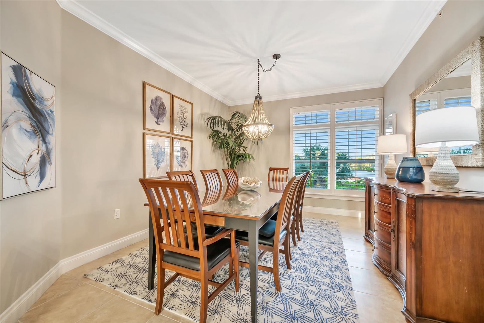 Gather around this elegant dining table beneath a beautiful chandelier for memorable meals with loved ones. Warm wood tones and soft natural light create the perfect ambiance for your vacation dining experience.