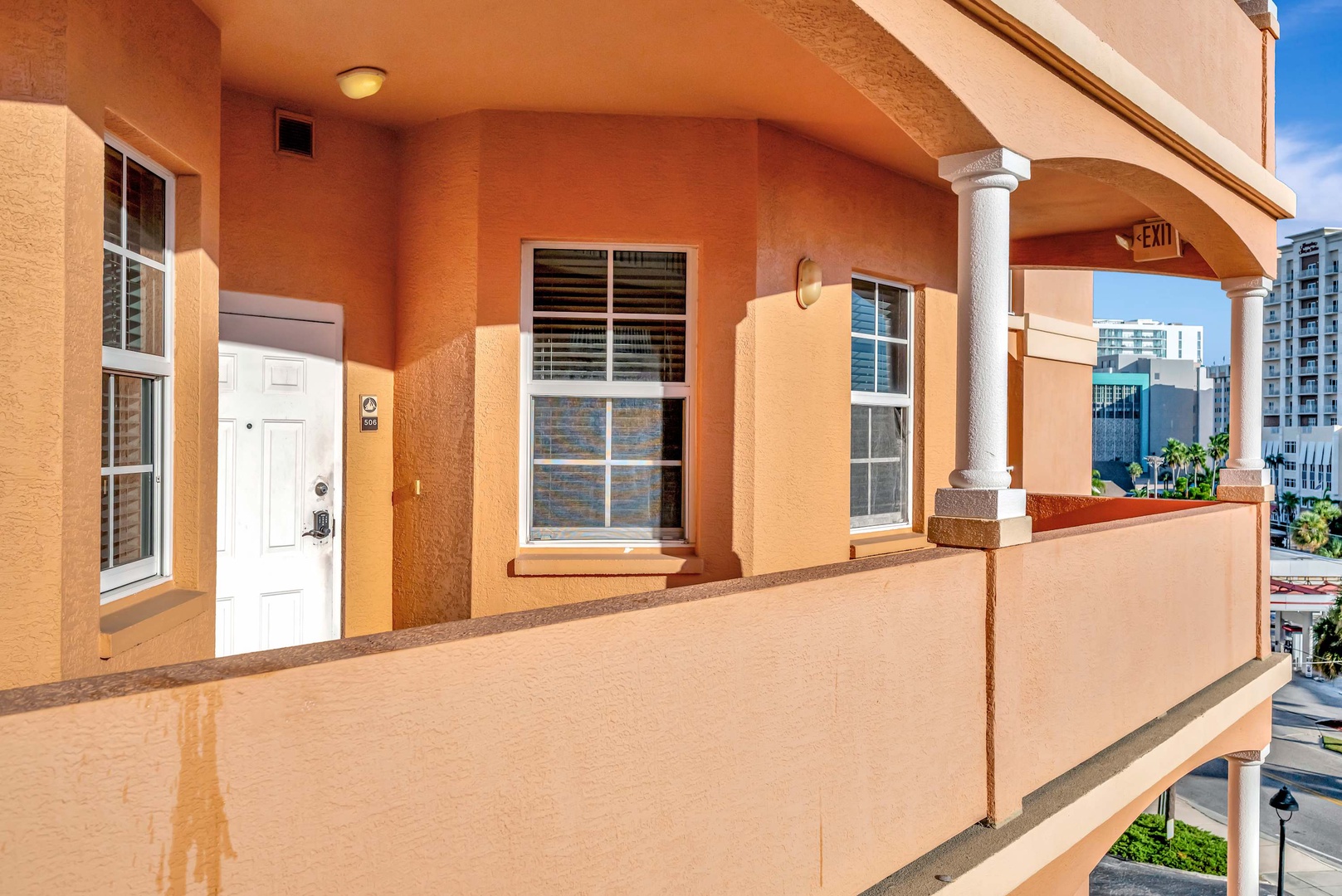 The property features a Mediterranean-style exterior with warm terracotta stucco and classic archways, located in a vibrant urban neighborhood with city views.
