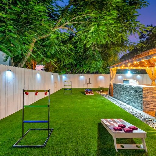 Your private backyard retreat features lush artificial turf, fun lawn games, and a covered hot tub area with warm lighting—perfect for evening relaxation under the stars.