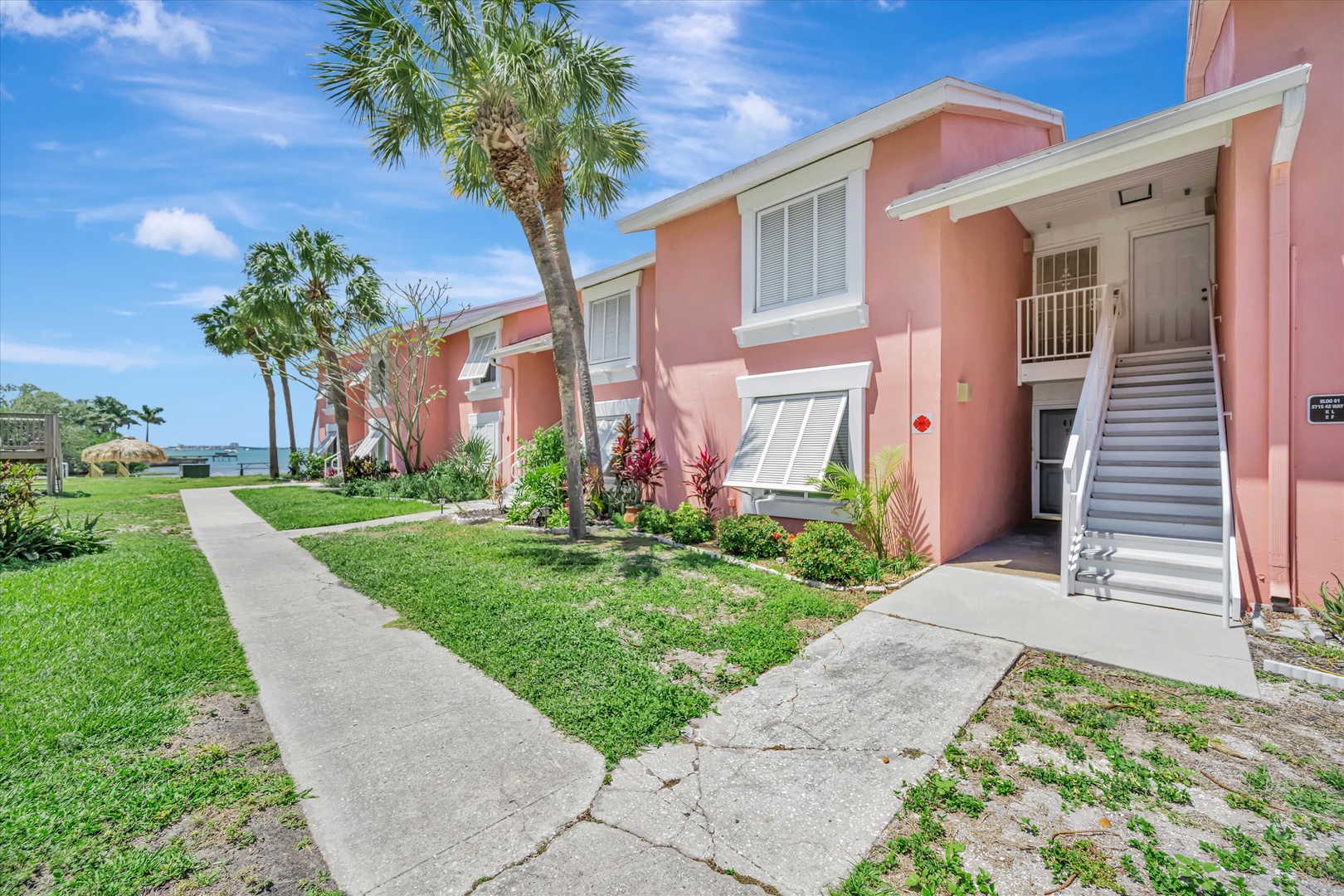 Charming coral-colored building nestled among swaying palms with glimpses of the water beyond, offering a tropical beachside setting for your getaway.