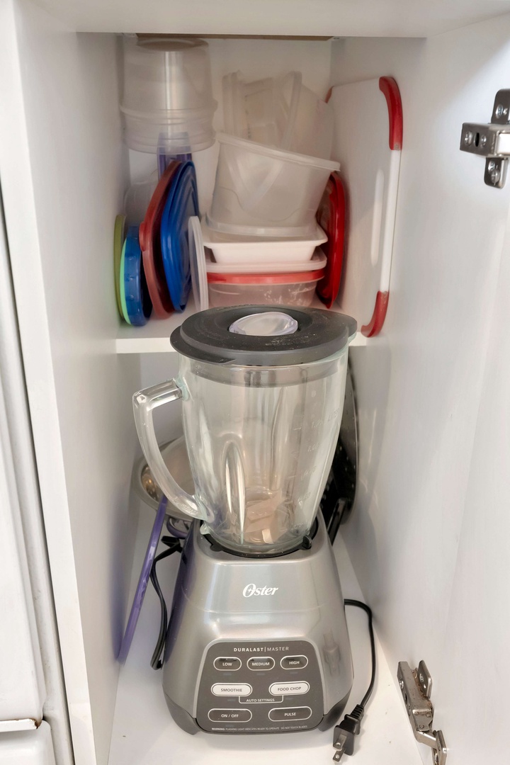 Smart storage keeps your kitchen essentials within easy reach—blender, plates, and food containers neatly organized in the cabinet.