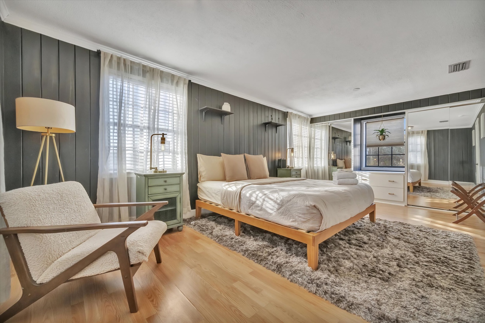 Step into your serene bedroom retreat with rich wood paneling, soft neutral bedding, and a cozy reading chair bathed in natural light—your personal sanctuary awaits.
