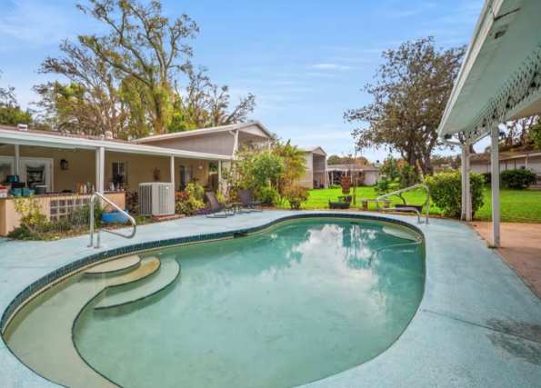 The property offers a private pool surrounded by lush gardens and mature trees, perfect for relaxing under sunny skies.
