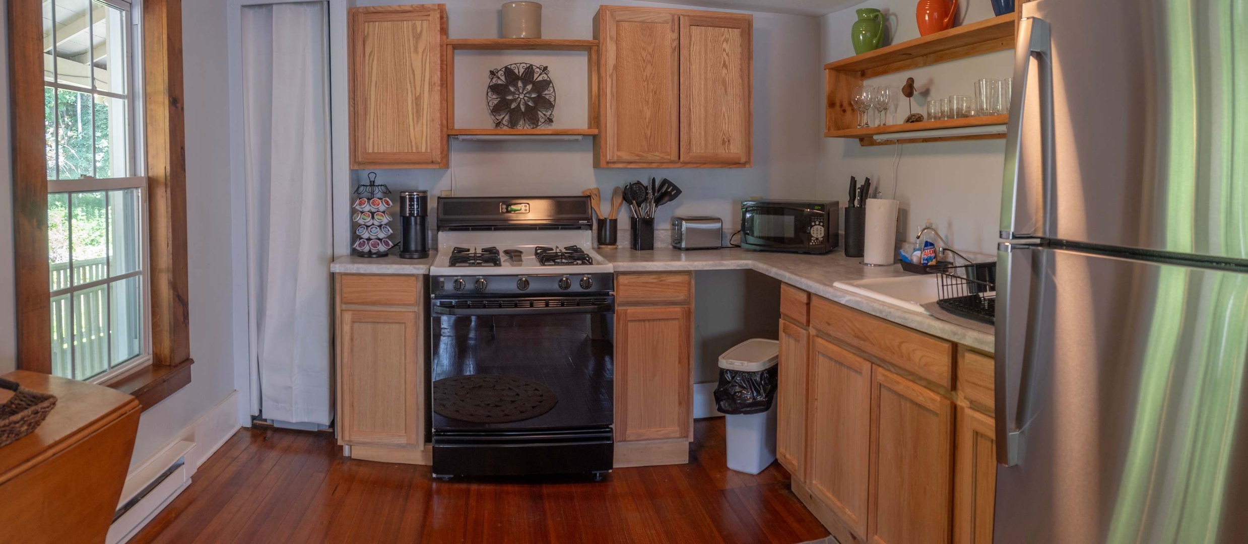 Your fully equipped kitchen has everything you need to prepare home-cooked meals, with a gas range, microwave, and full-size refrigerator. Natural light streams in through the window, making this a welcoming space for cooking and gathering.