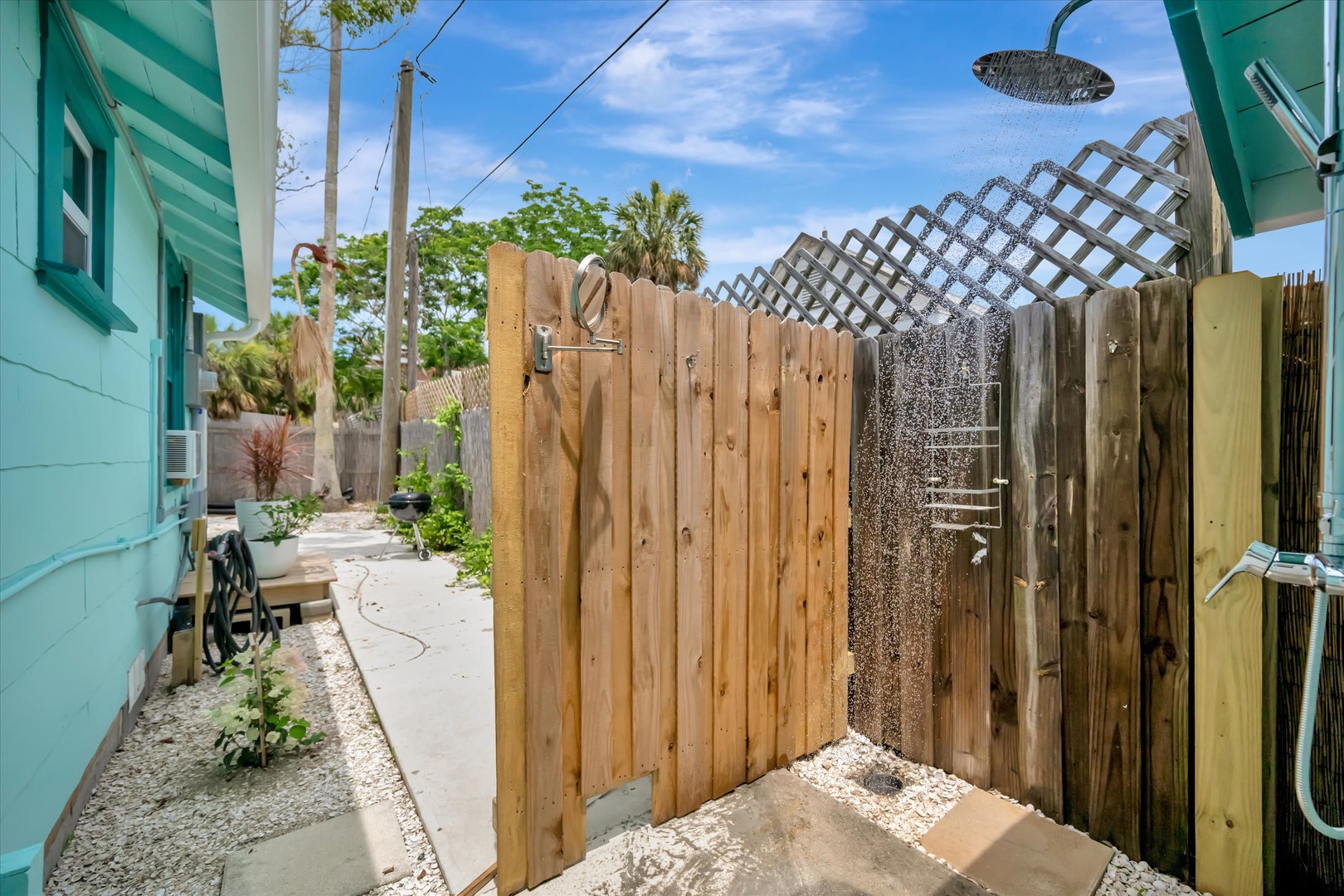 Step into your private open-air shower surrounded by tall wooden fencing and lush tropical palms overhead—a refreshing outdoor escape after a sunny day.