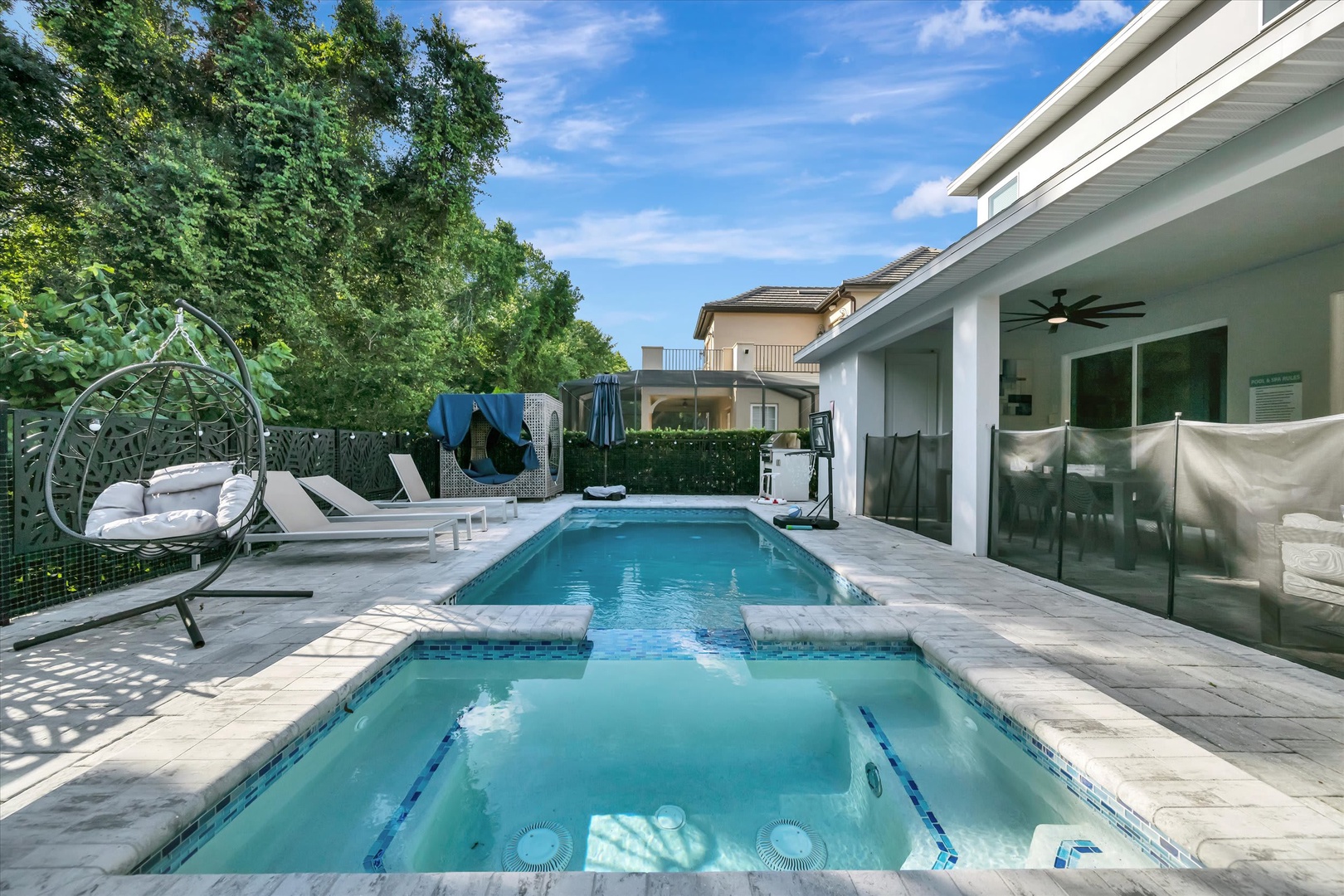 The property features a private pool and hot tub surrounded by elegant patio seating, creating a perfect retreat for sunny days spent lounging under the blue sky.