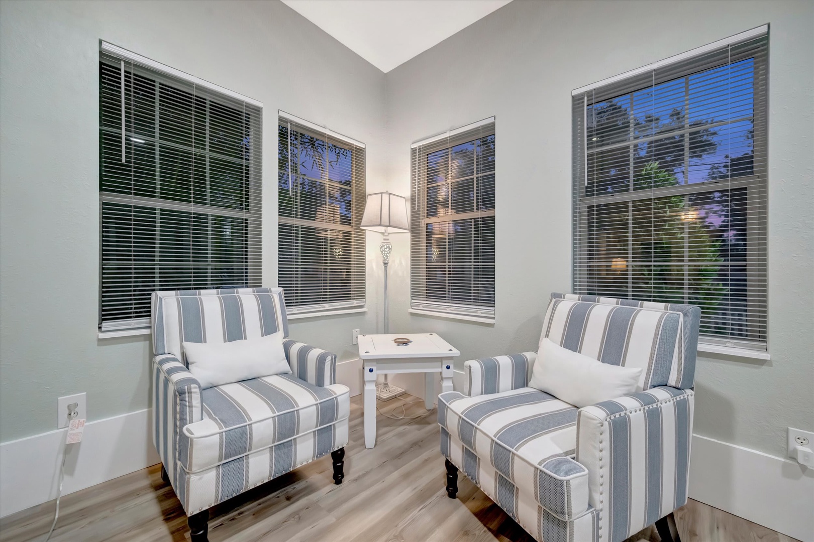 Sink into the comfort of your private reading nook, where striped coastal chairs and soft light create the perfect spot to unwind with a good book or evening conversation.