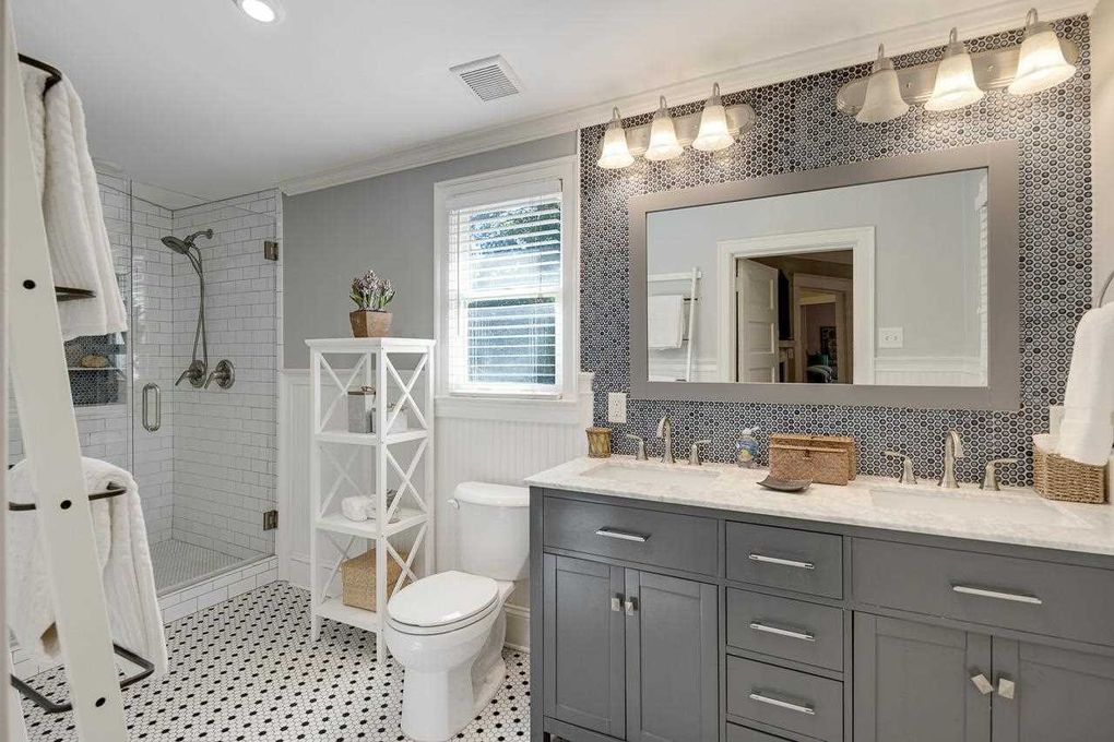 Your beautifully designed bathroom features a spacious dual-sink vanity with elegant penny tile accents, a walk-in shower with subway tile, and soft natural light to start your mornings right.