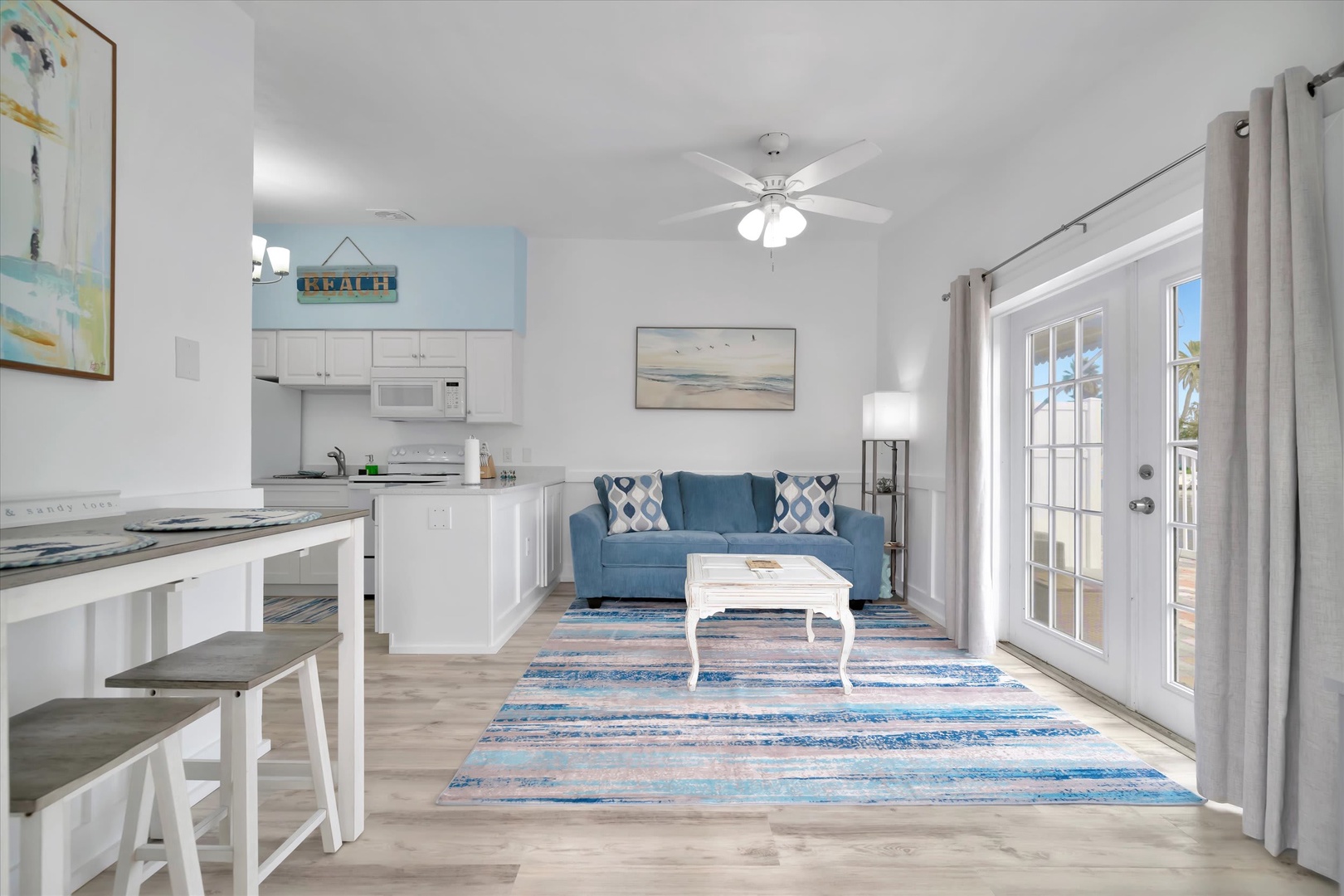 Step into your bright, coastal-inspired retreat with an open layout that flows effortlessly from kitchen to living space. Blue accents and beach-themed art set a relaxing tone, while French doors invite you onto your private patio.
