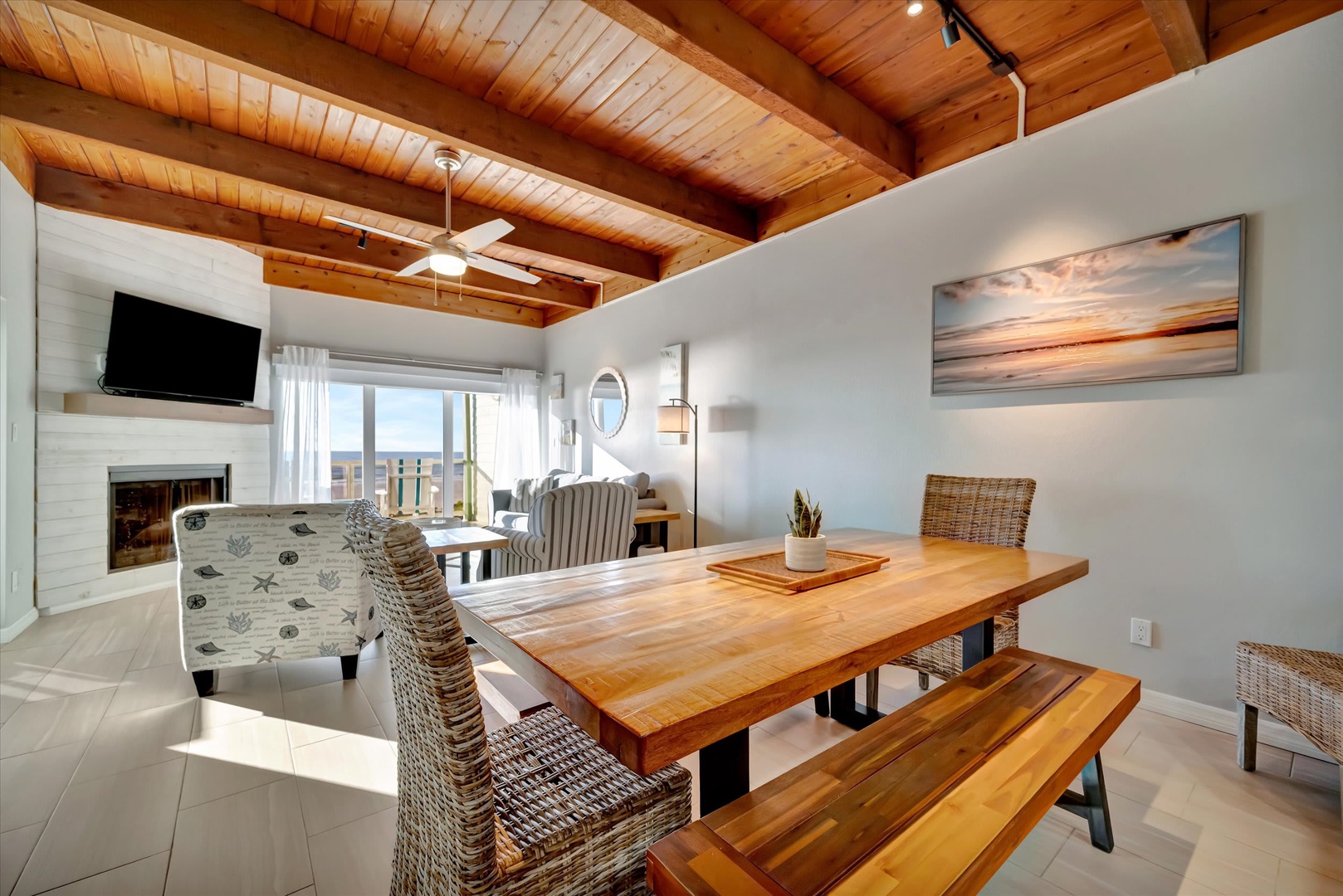 Gather around a beautiful live-edge dining table beneath soaring wood-beamed ceilings. Natural light floods the open-concept space, where your cozy fireplace and comfy seating await after meals shared with loved ones.