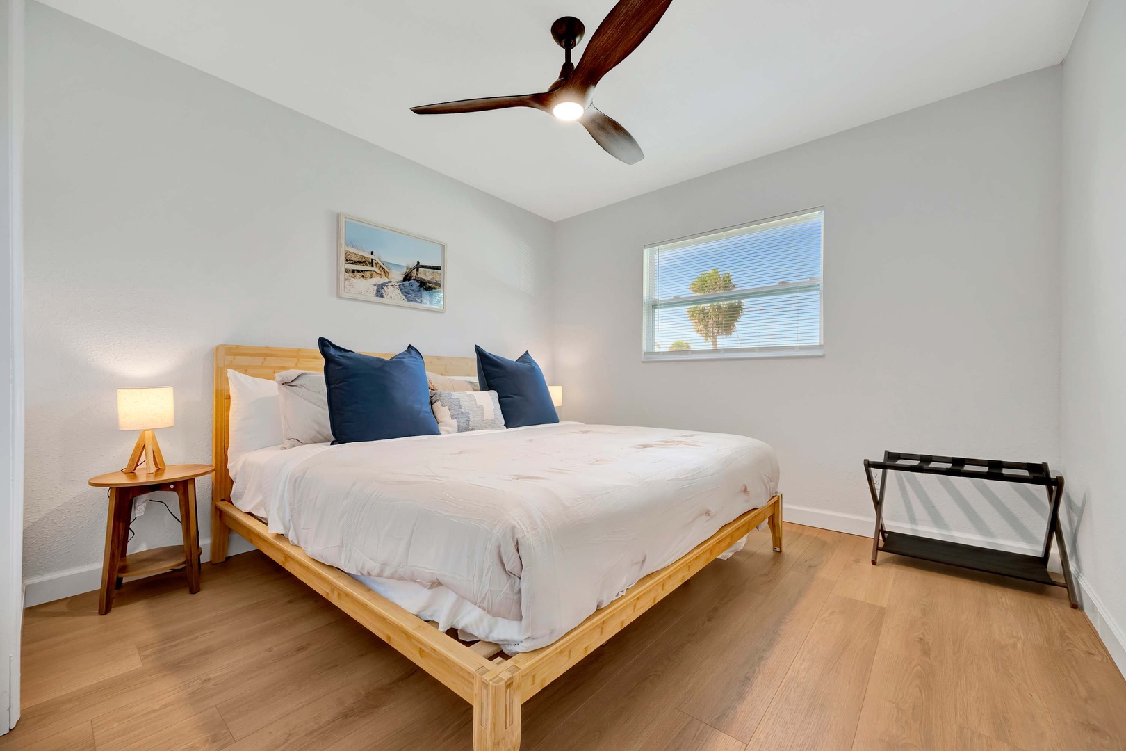 Slip into crisp white linens and let the ceiling fan's gentle breeze lull you to sleep. Natural light filters through the window, and a luggage rack awaits your arrival.