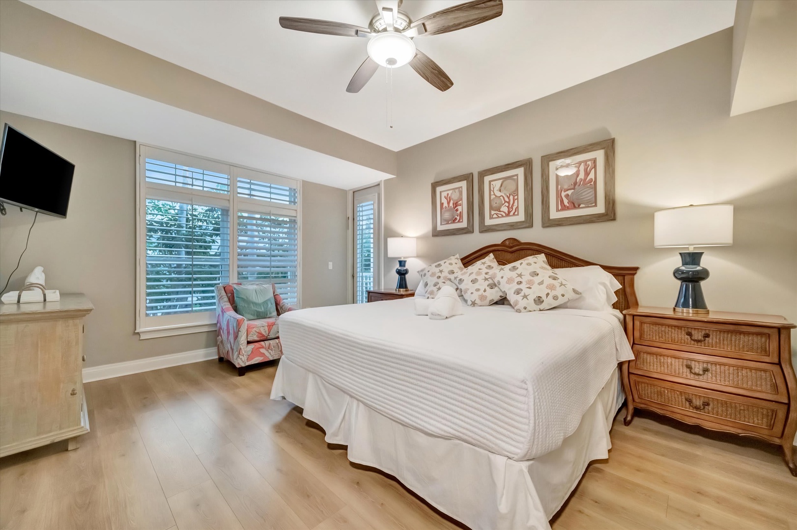 Sink into crisp linens and let the ceiling fan's gentle breeze lull you to sleep in this serene bedroom retreat with natural light streaming through plantation shutters.