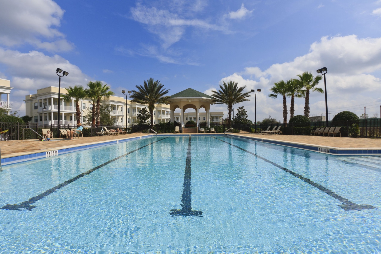 The expansive lap pool with its classic pavilion and palm-lined deck creates your perfect backdrop for morning swims or relaxed afternoons under sunny skies.