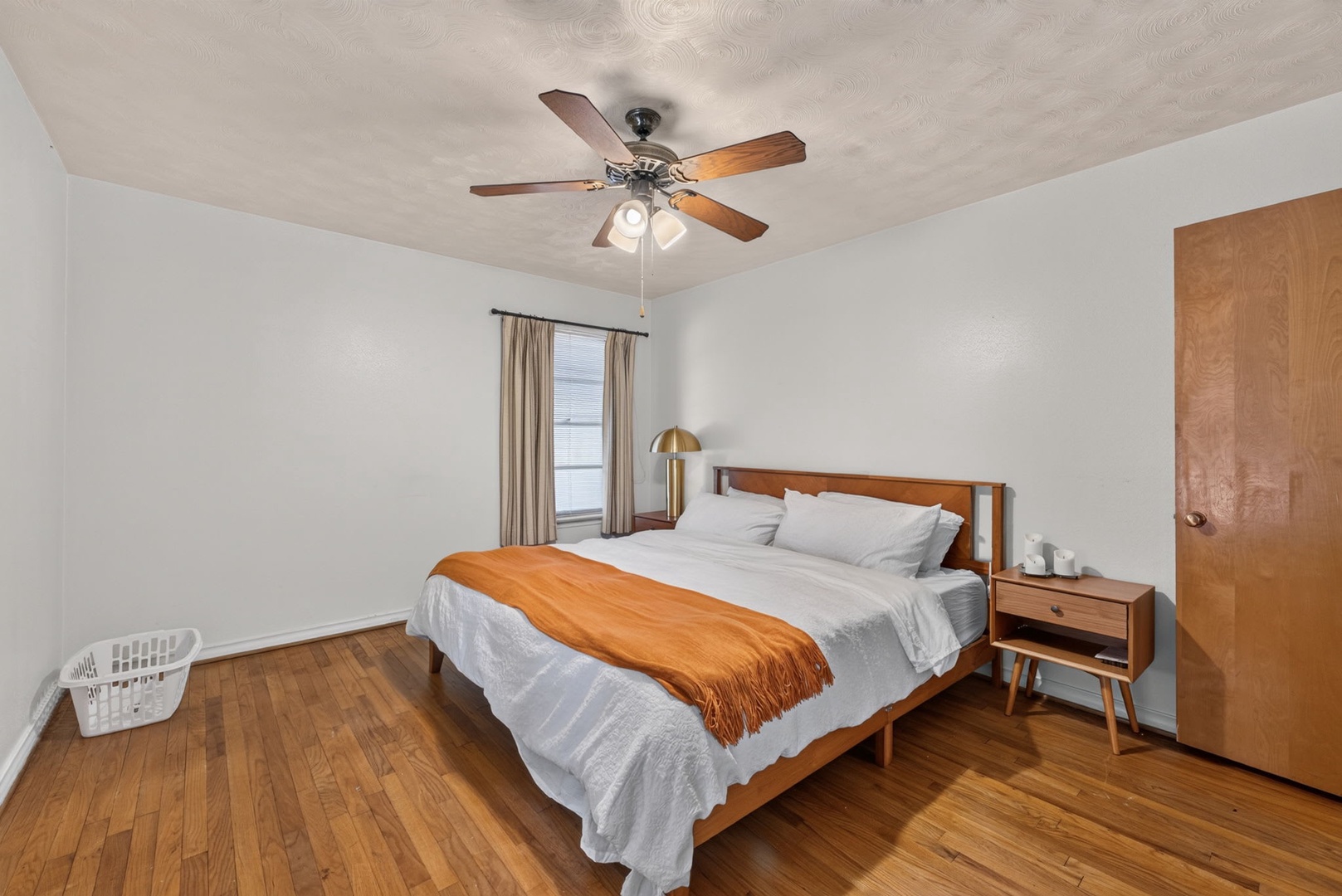 Slip into crisp linens and let the ceiling fan's gentle breeze lull you to sleep in this cozy bedroom with warm wood accents throughout.