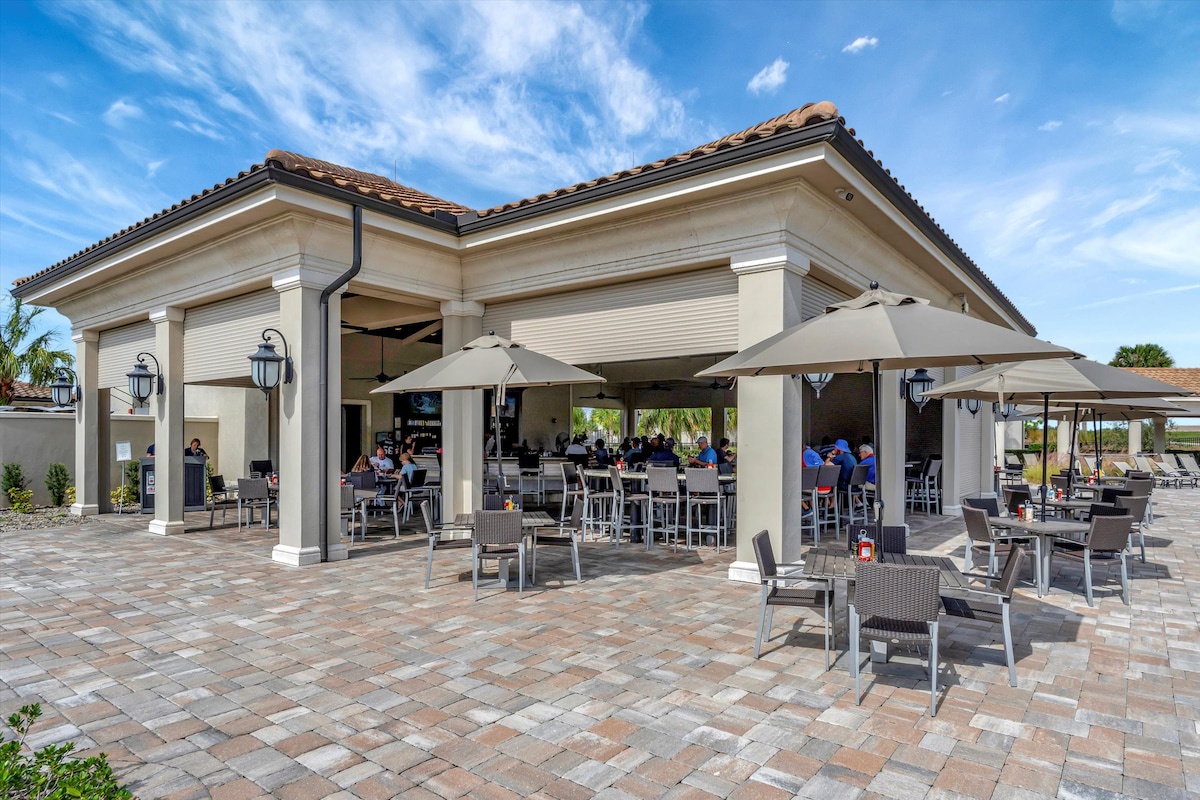 This elegant outdoor bar and dining pavilion offers a perfect gathering spot, with comfortable seating beneath shaded umbrellas where you can enjoy drinks and meals while taking in the beautiful Florida sunshine.