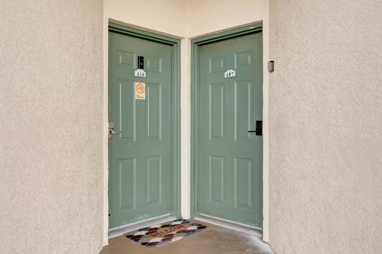 Two side-by-side unit entrances with sage green doors and keyless entry systems mark your arrival, making check-in effortless and secure for a truly modern getaway.
