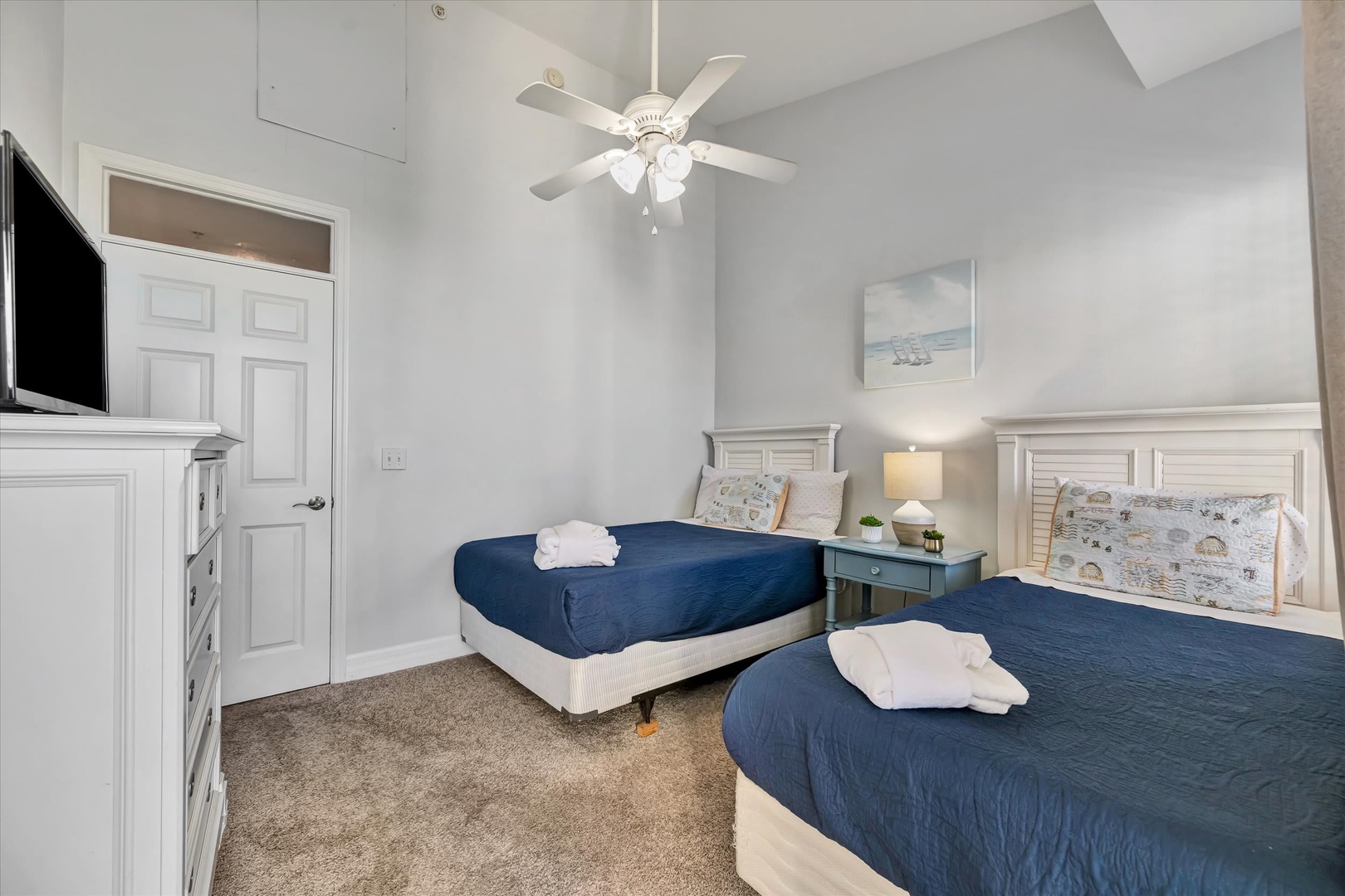 Settle into your bright, airy bedroom with two comfortable beds dressed in crisp navy linens and plush towels awaiting. Coastal décor and vaulted ceilings create a peaceful retreat after a day of exploration.