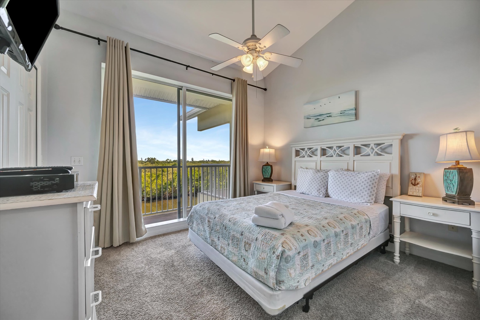Wake up to serene nature views through the glass doors of your private bedroom retreat. Sink into the plush bed adorned with coastal-inspired linens, and drift off under the gentle hum of the ceiling fan as natural light fills your space.