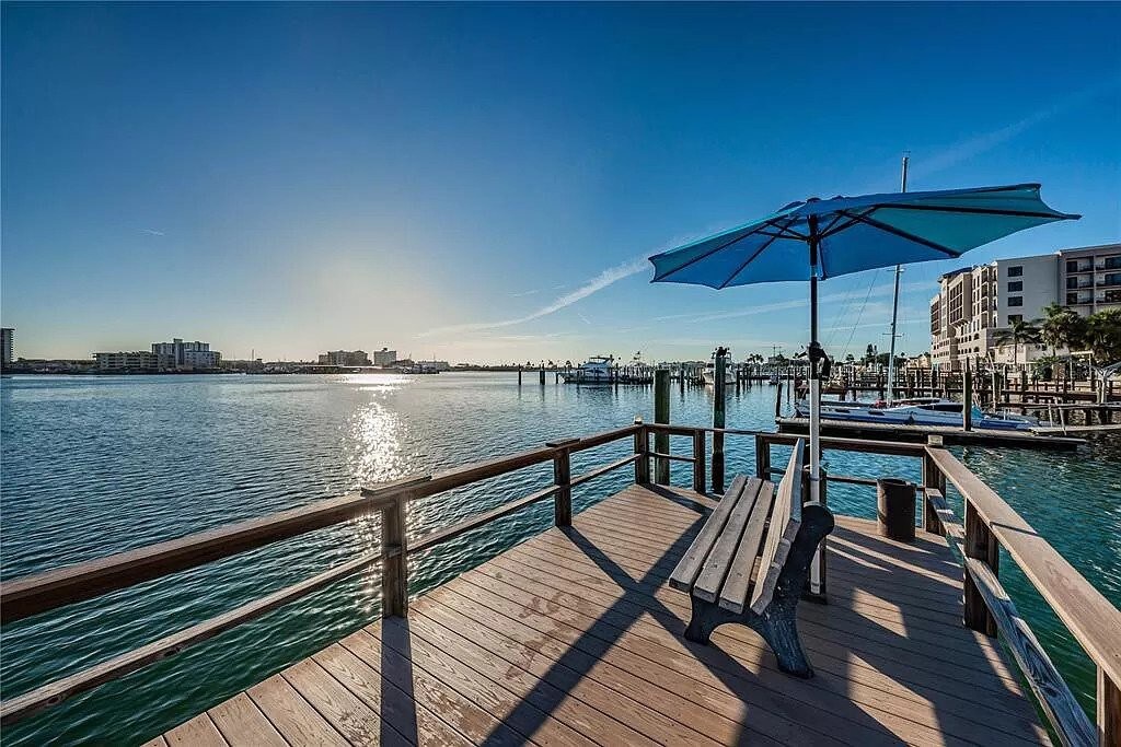 A private waterfront dock with covered seating overlooks a serene bay, with palm-lined shores and sunlit waters stretching toward the horizon—perfect for morning coffee or evening relaxation.