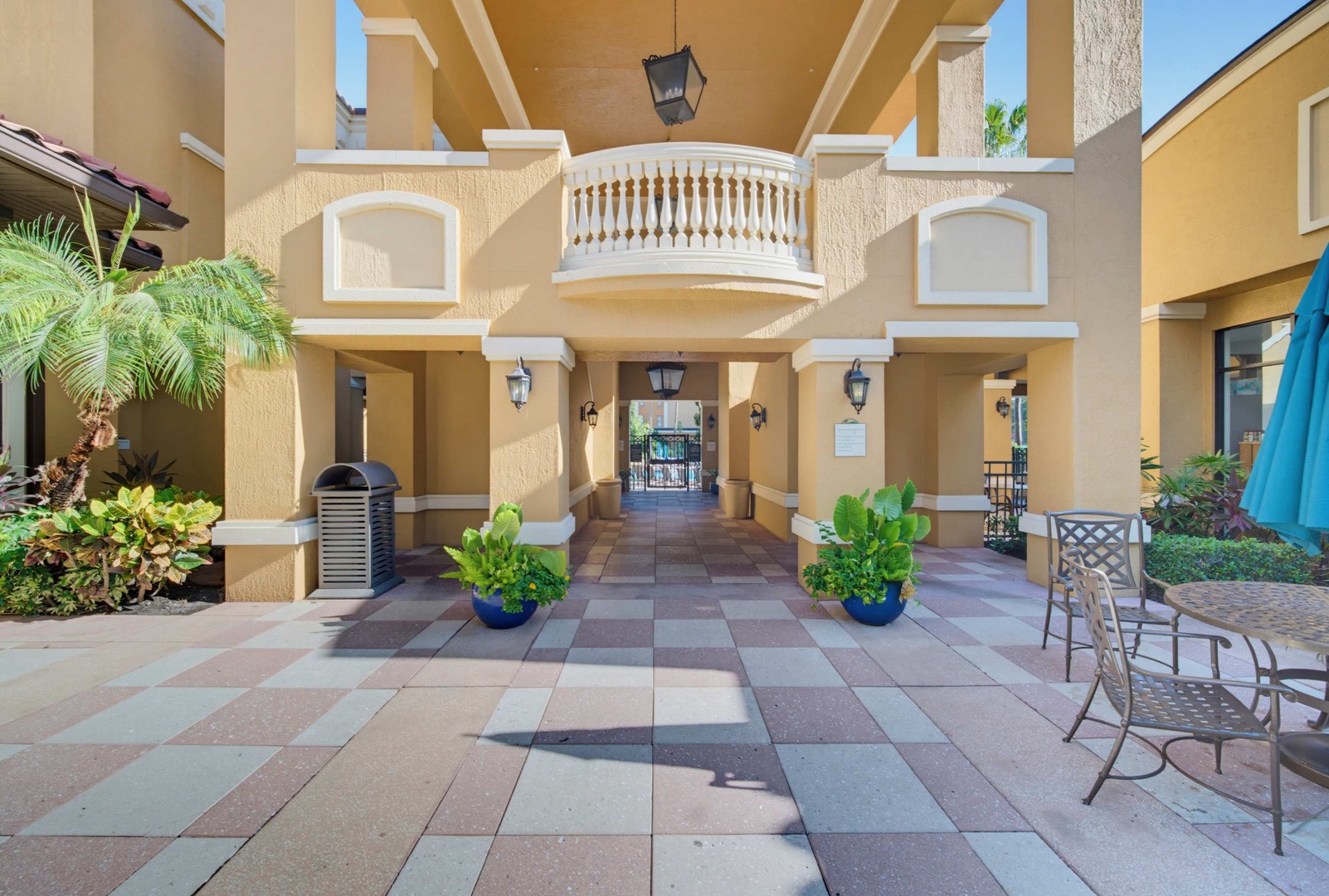 This stately entrance features beautiful Mediterranean-inspired architecture with warm columns, elegant balconies, and lush tropical landscaping—a grand welcome to your vacation retreat.