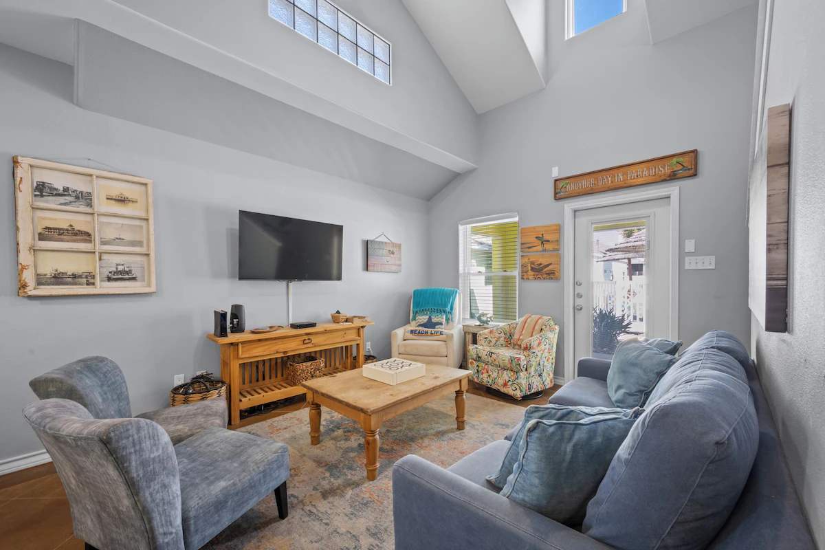 Settle into this bright, airy living space where vaulted ceilings and natural light create an open, welcoming atmosphere. Cozy seating invites you to relax after a day of exploring, with the door to your private outdoor area just steps away.