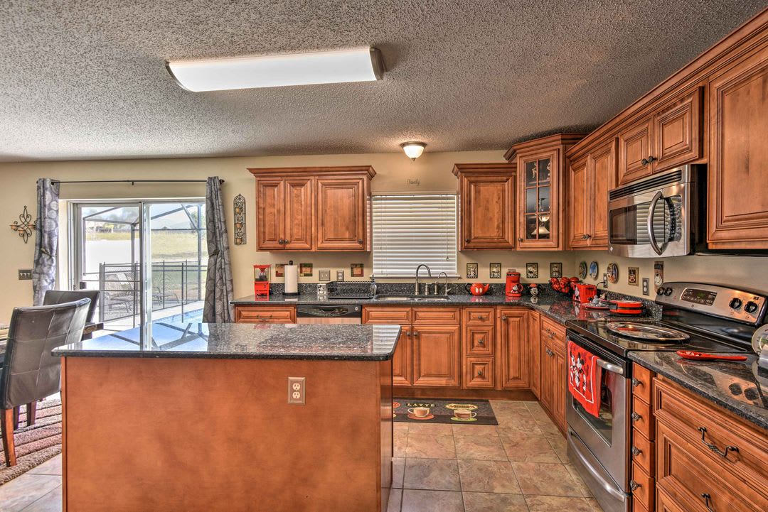 Step into your fully-equipped kitchen with rich wood cabinetry, granite countertops, and a spacious island—perfect for preparing meals or sharing morning coffee with lake views just beyond the glass doors.