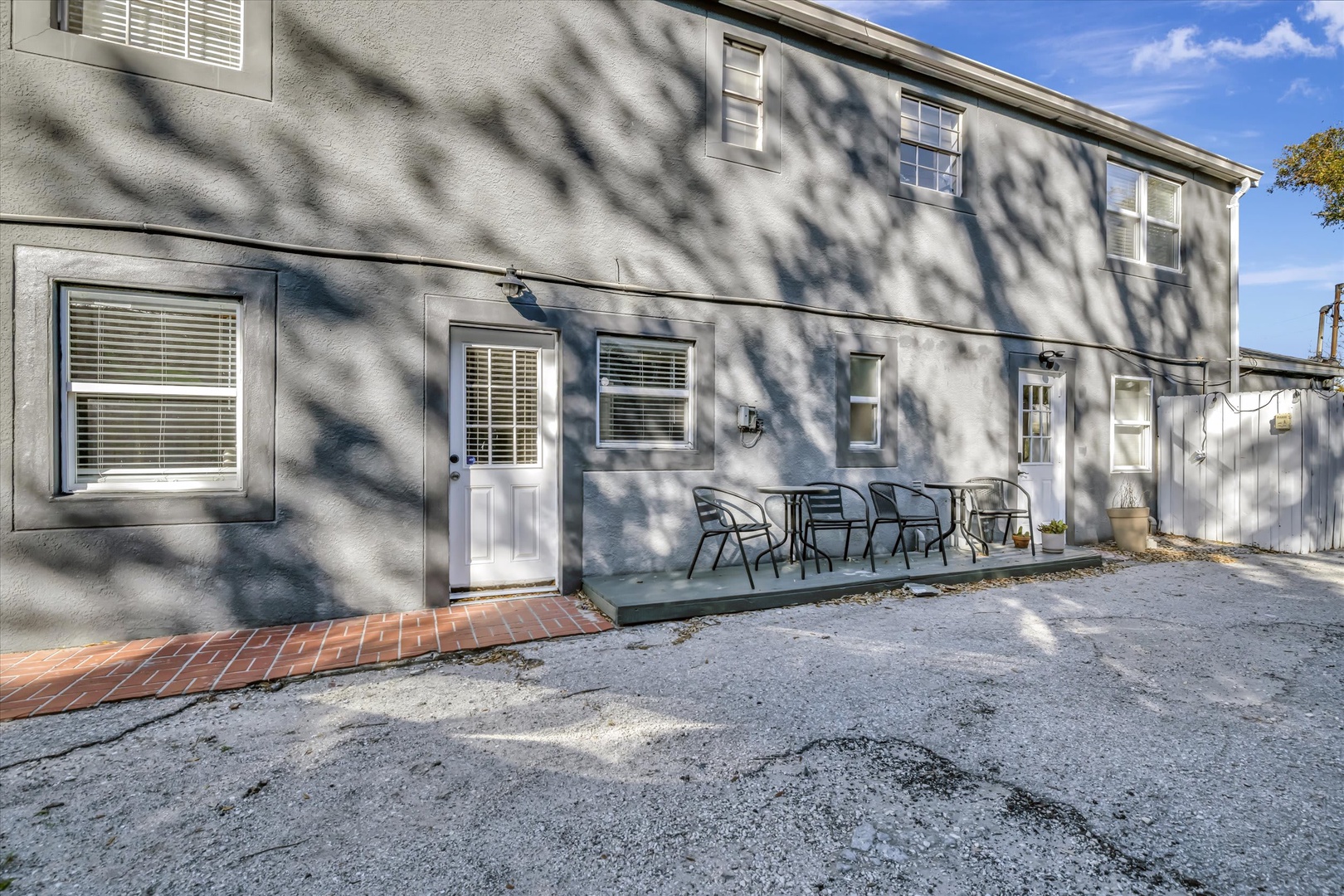 The property exterior features outdoor seating space on a small patio with shaded tree canopy overhead. A convenient private entrance and dedicated parking area complete this charming arrival experience.