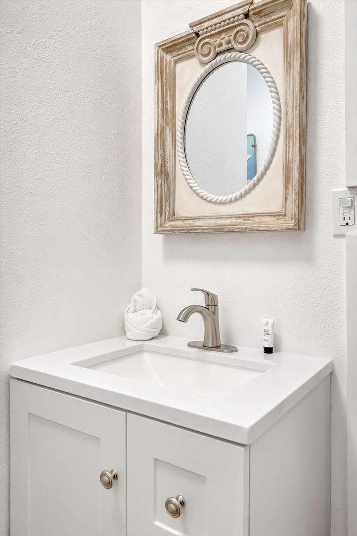 A peaceful powder room awaits with classic charm—your own elegant vanity with a decorative oval mirror and pristine white sink creates a refined space for freshening up.