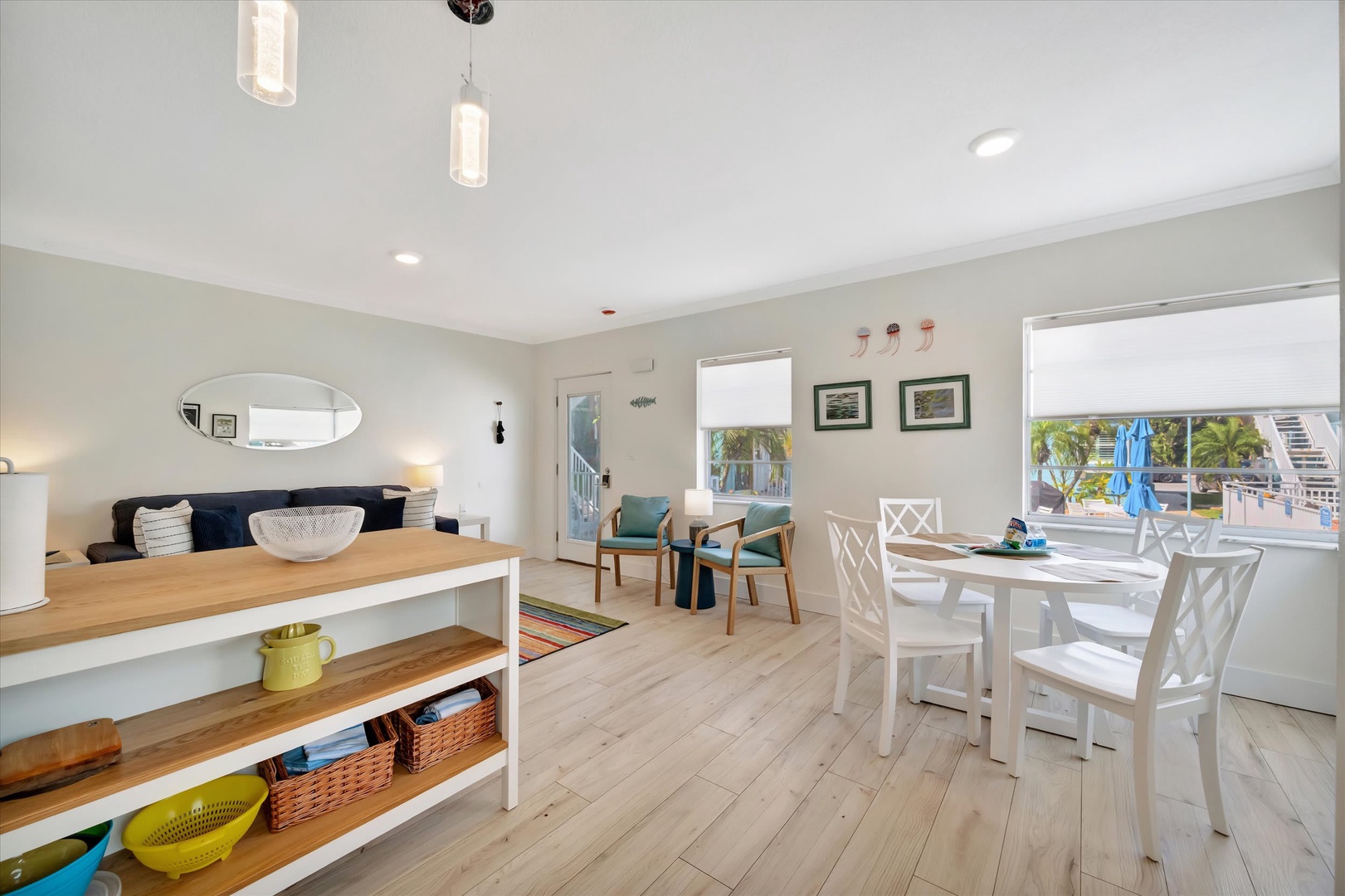 Bright, breezy coastal retreat with expansive windows framing tropical palm views. Open-concept living space perfect for dining, relaxing, and entertaining during your getaway.