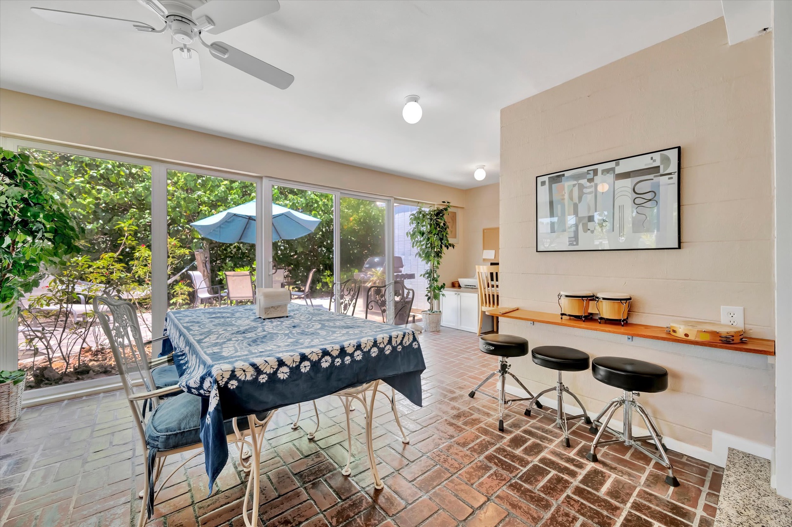 Your bright, airy dining space opens onto a charming patio through expansive glass doors, blending indoor comfort with outdoor relaxation. Dine at the vintage table, then step outside to lush greenery and umbrella-shaded seating.