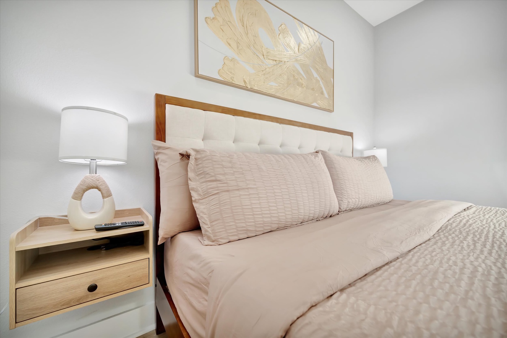 Sink into plush bedding in this serene bedroom, where soft lighting and warm wood tones create your perfect retreat after a day of exploring.
