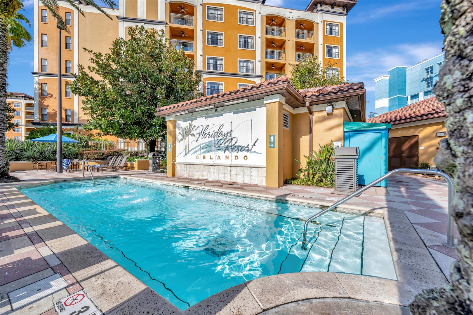The resort's outdoor pool area, framed by swaying palms and Mediterranean-style architecture, with lounge seating nearby for your perfect Orlando escape.