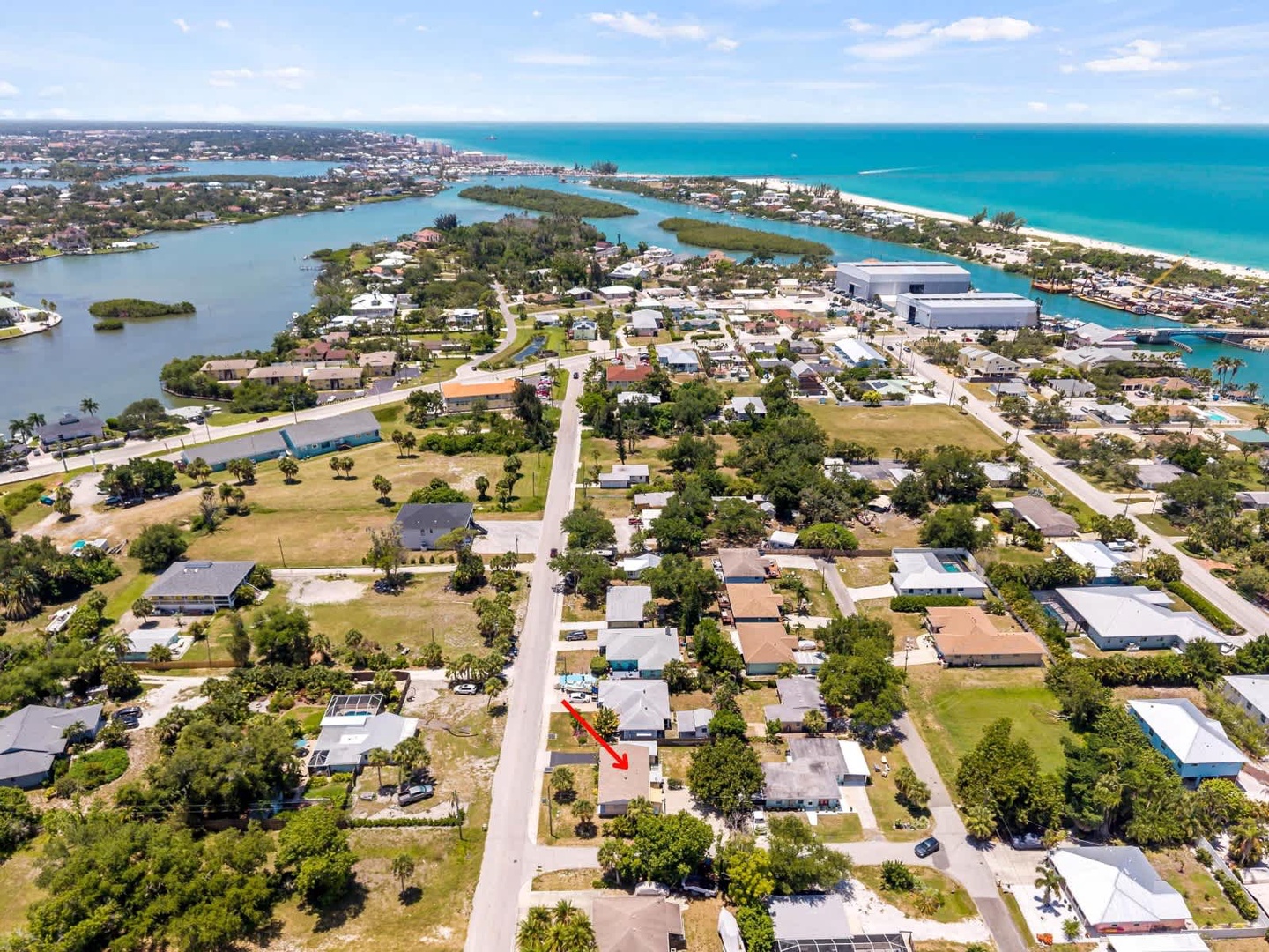 Aerial view of a coastal community featuring waterways, beaches, and residential neighborhoods with easy access to turquoise waters and sandy shores.