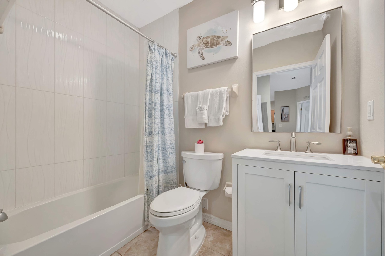 Step into your bright, coastal-inspired bathroom with fresh white tiles, a soothing sea turtle accent, and soft towels waiting for you after a relaxing soak.