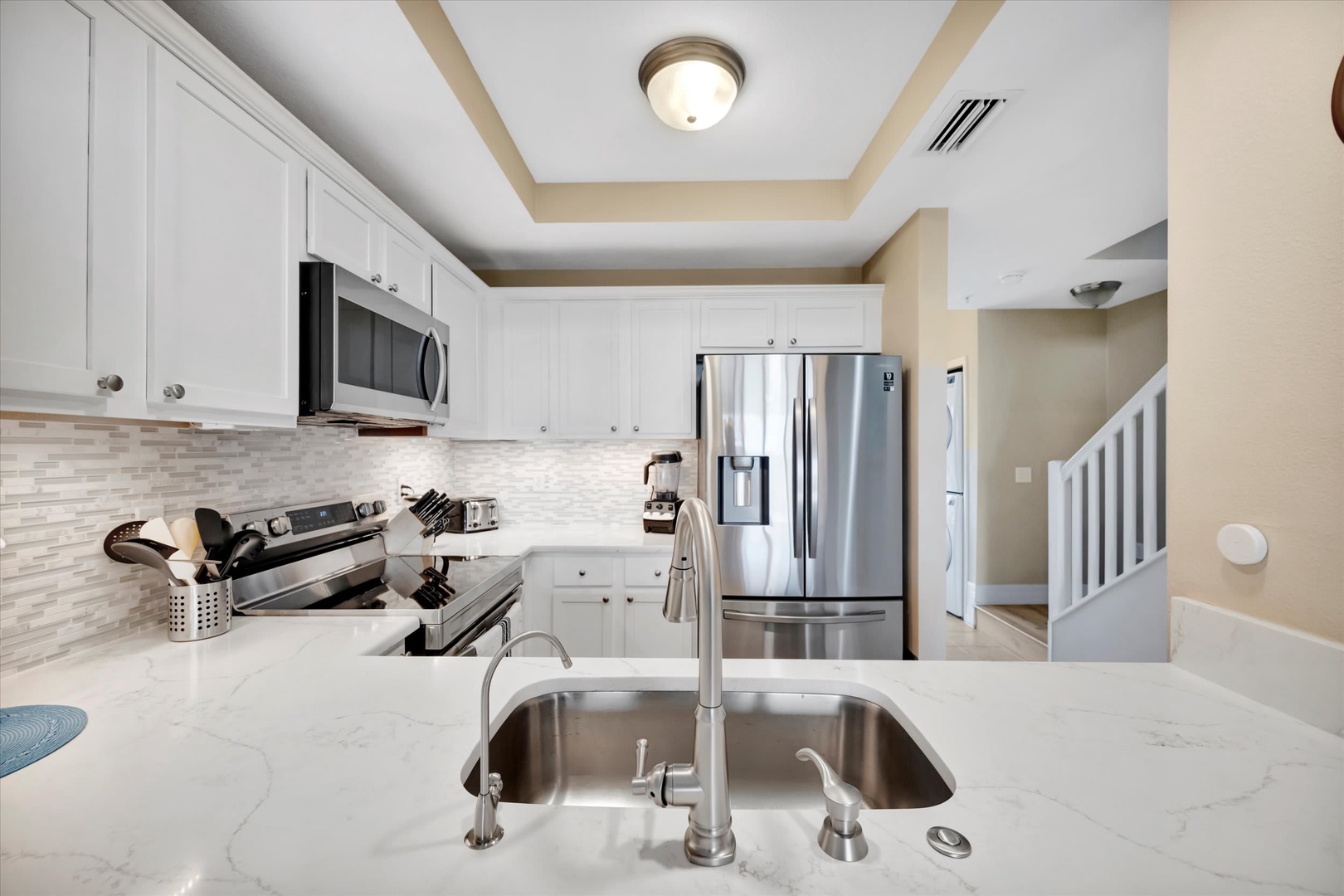 Your fully equipped kitchen features sleek marble countertops, stainless steel appliances, and crisp white cabinetry—everything you need to prepare meals in comfort and style.