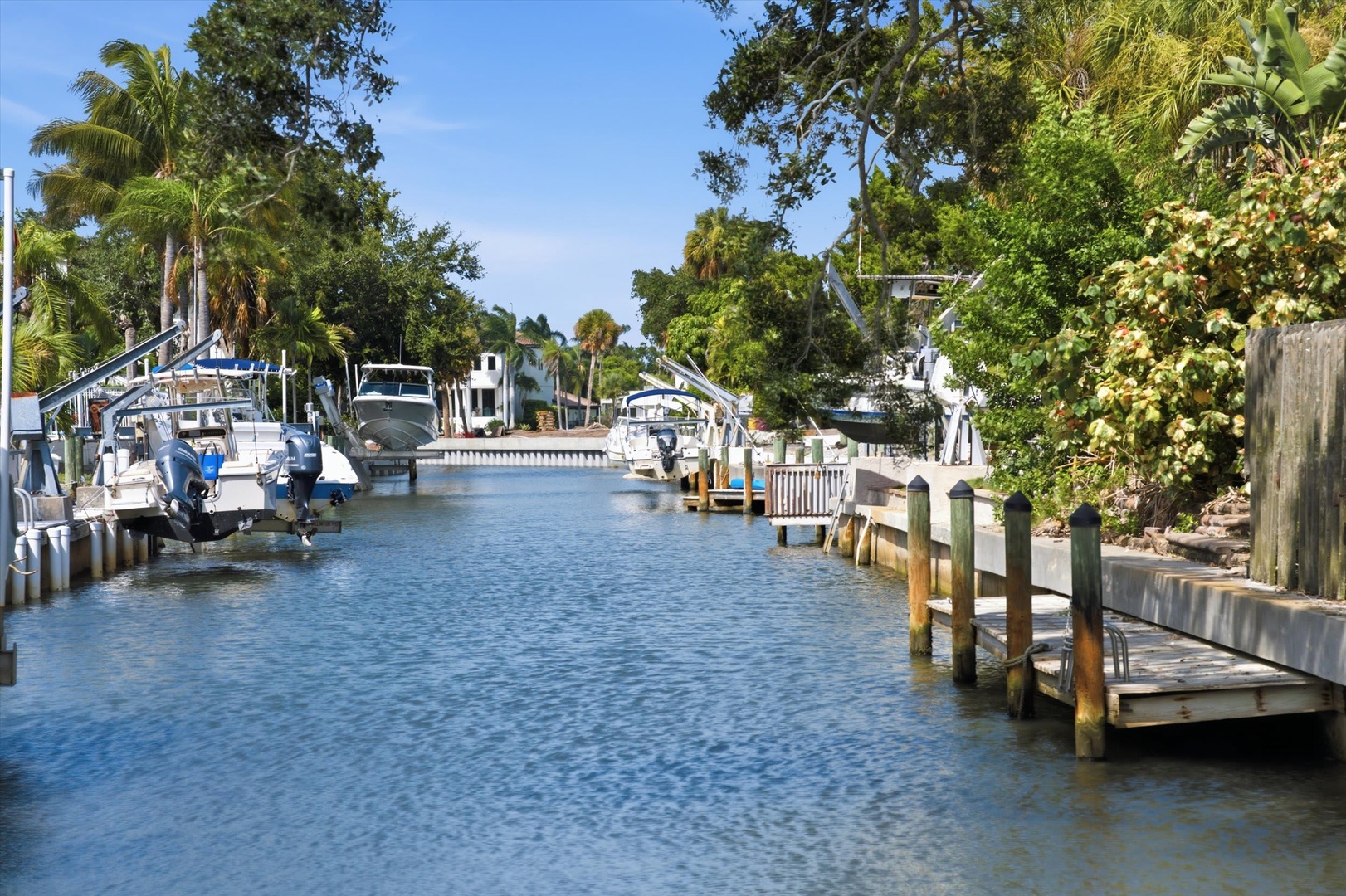 The property sits along a peaceful canal lined with palm trees and tropical foliage, offering boat access and a serene waterfront setting.