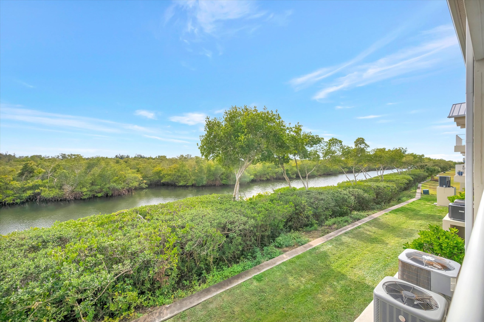 Wake up to tranquil river views framed by lush greenery right outside your door. Enjoy morning coffee while soaking in the peaceful natural landscape and blue skies beyond.