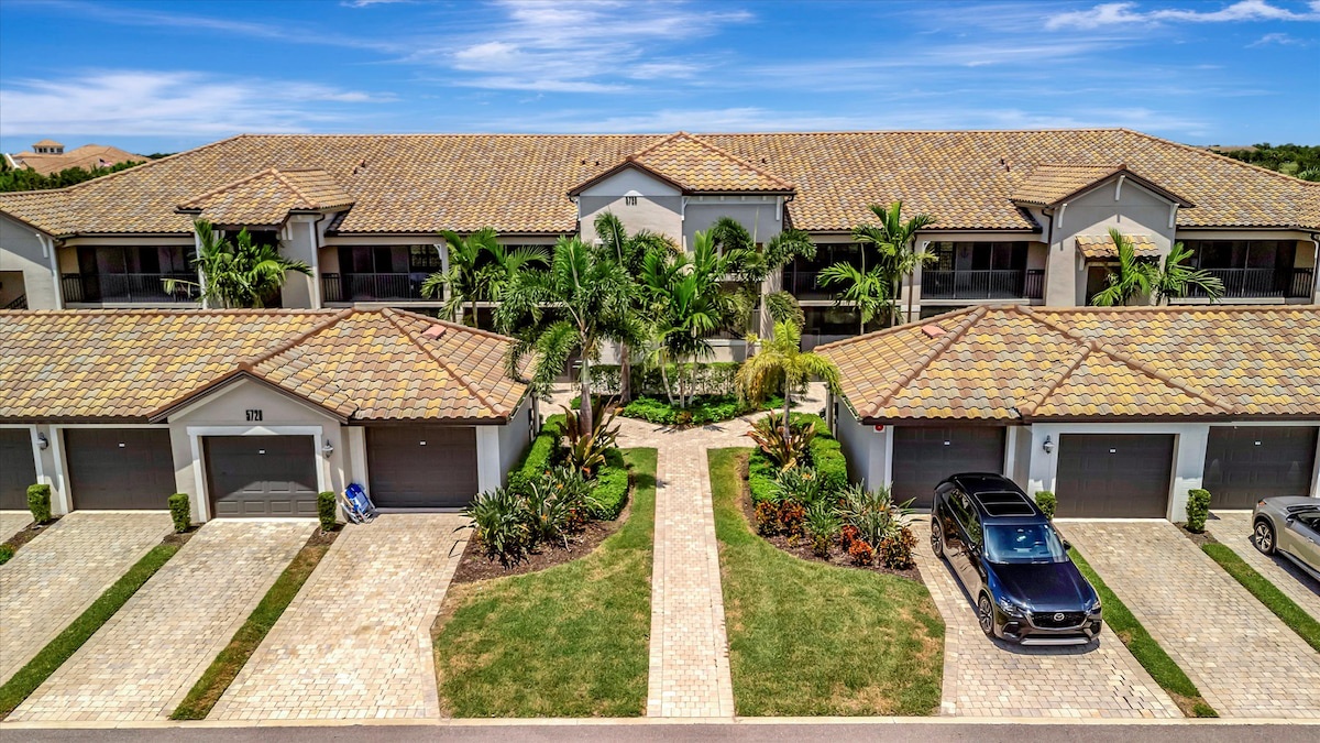 Aerial view of the property showcasing Mediterranean-style architecture with tile roofing, private garages, and tropical landscaping throughout the complex.