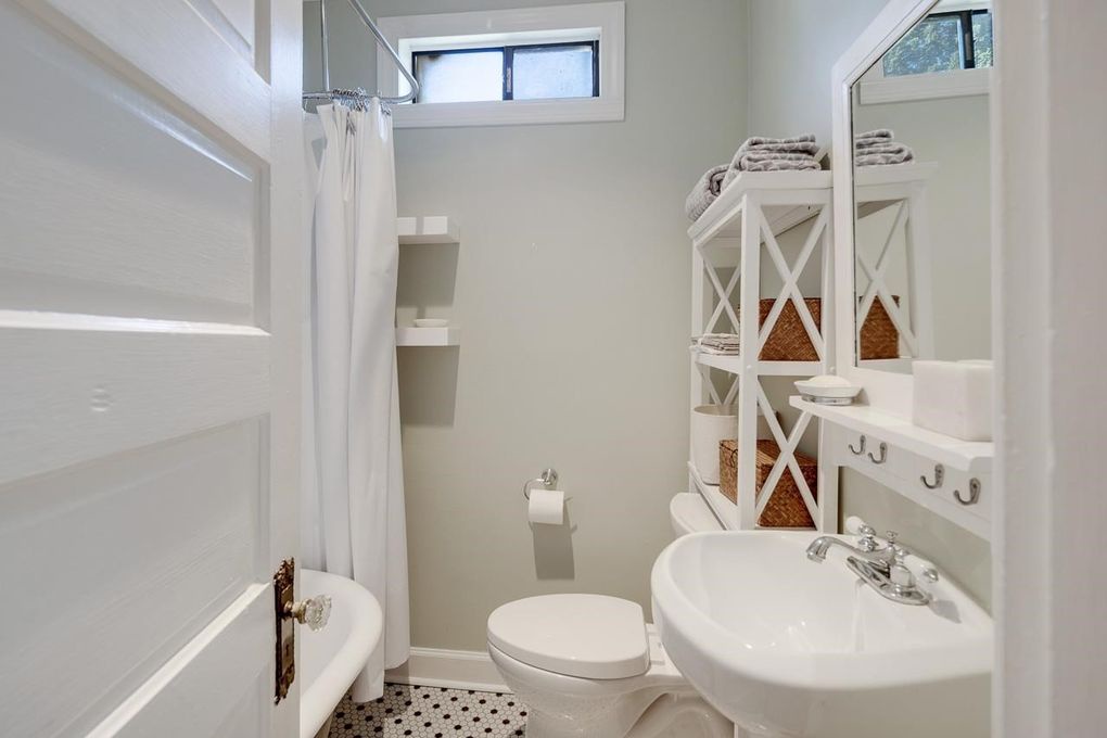 Step into your bright, spotless bathroom with fresh towels waiting and charming vintage-style storage to keep everything organized. The tub invites you to unwind after a day exploring nearby attractions.