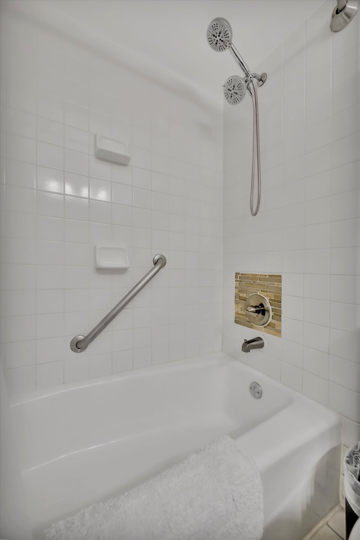 Refresh after a day of exploring in this bright, modern bathroom featuring a soothing soaking tub, dual showerheads, and thoughtful grab bars for your comfort and safety.