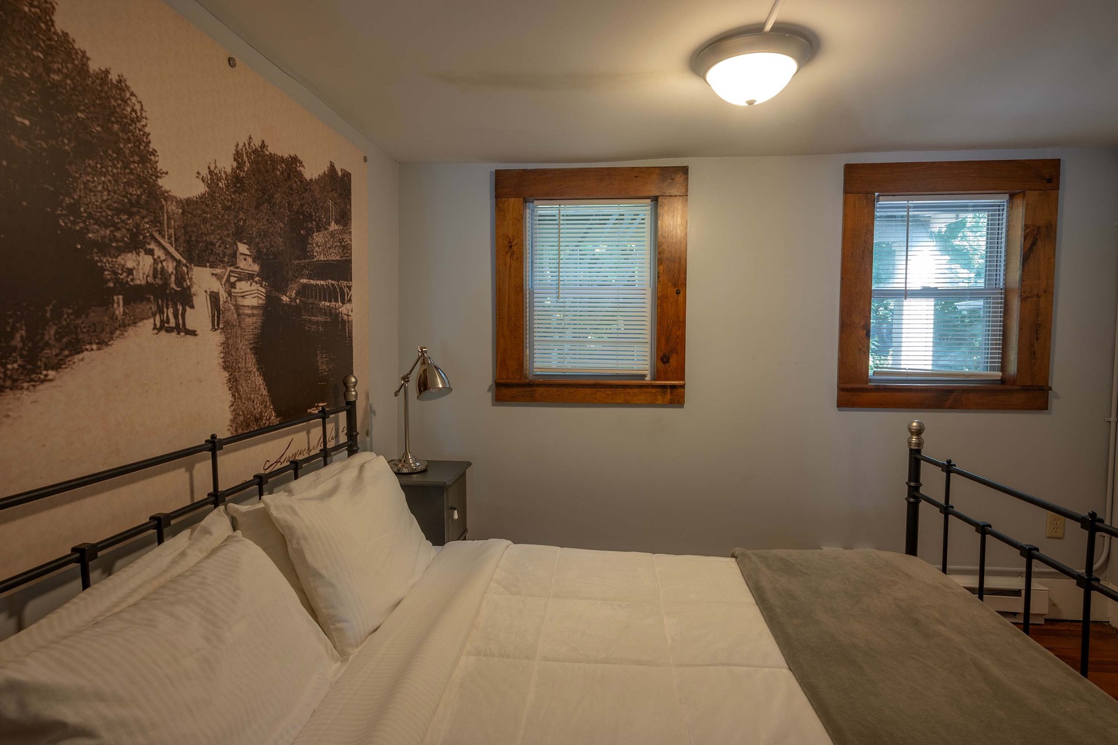Sink into crisp linens in your cozy bedroom, where natural light streams through charming wood-framed windows and vintage-inspired touches invite peaceful rest.