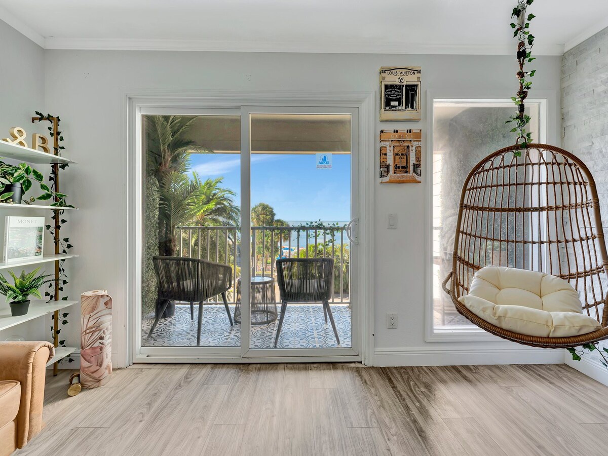 Settle into your cozy hanging chair and soak in the warm coastal breeze and lush palm views from your private balcony—your perfect retreat for morning coffee or sunset relaxation.